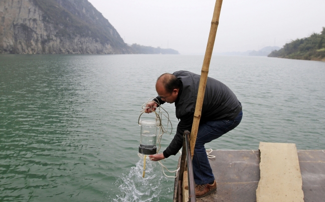 A man collects water samples from a polluted river in China. Photo: Reuters