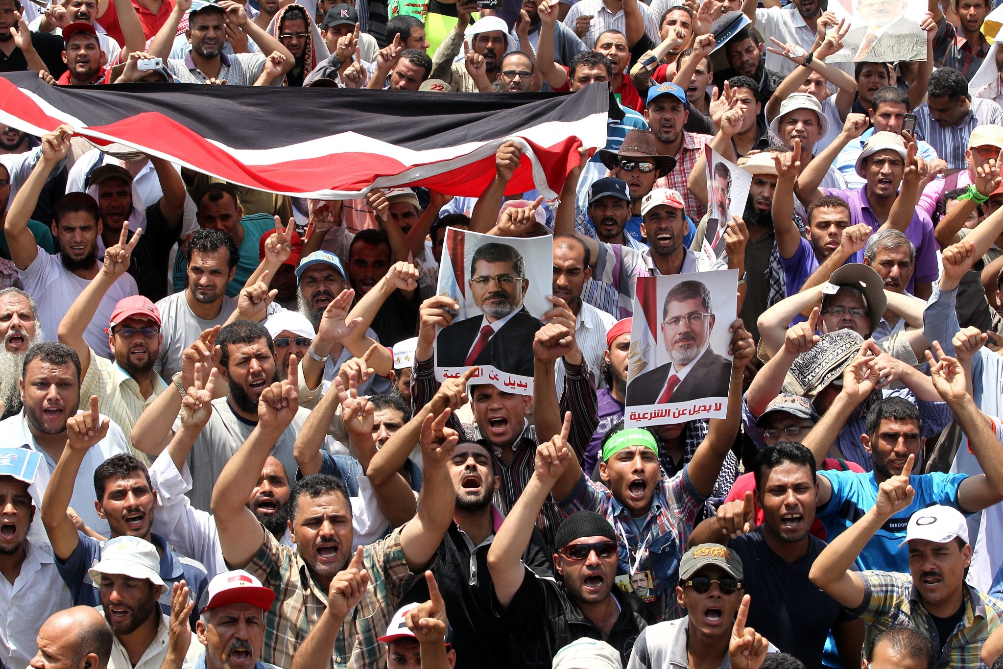 Egyptian supporters of ousted president Mohamed Morsi hold posters depicting Morsi and shout slogans as they protest outside Rabaa al-Adawiya mosque in Cairo in Egypt. Photo: EPA