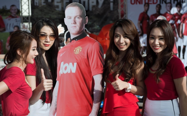 Thai models pose next to a life-sized cardboard cutout photograph of Manchester United's Wayne Rooney in Bangkok. Photo: AFP