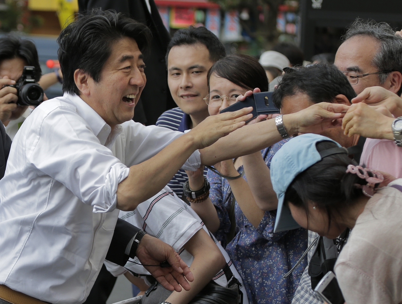 Japanese Prime Minister and the ruling Liberal Democratic Party's leader Shinzo Abe, left, greets audience during the last day of parliamentary upper house election campaign in Tokyo on Saturday. Photo: AP
