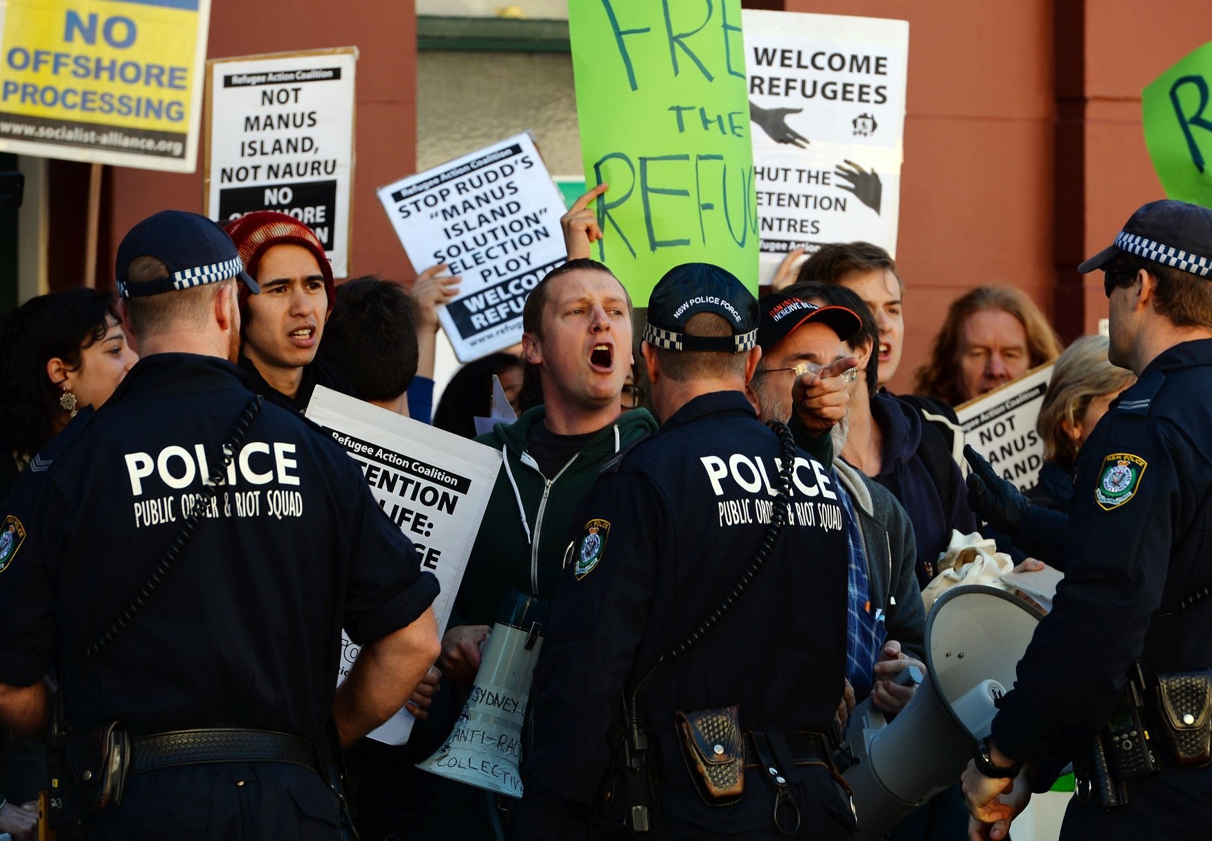 Police officers on Wednesday keep vigil as demonstrators shout slogans against the government's new policy of resettling refugees in Papua New Guinea as the ruling Labor party attended a caucus meeting in Sydney. Photo: AFP
