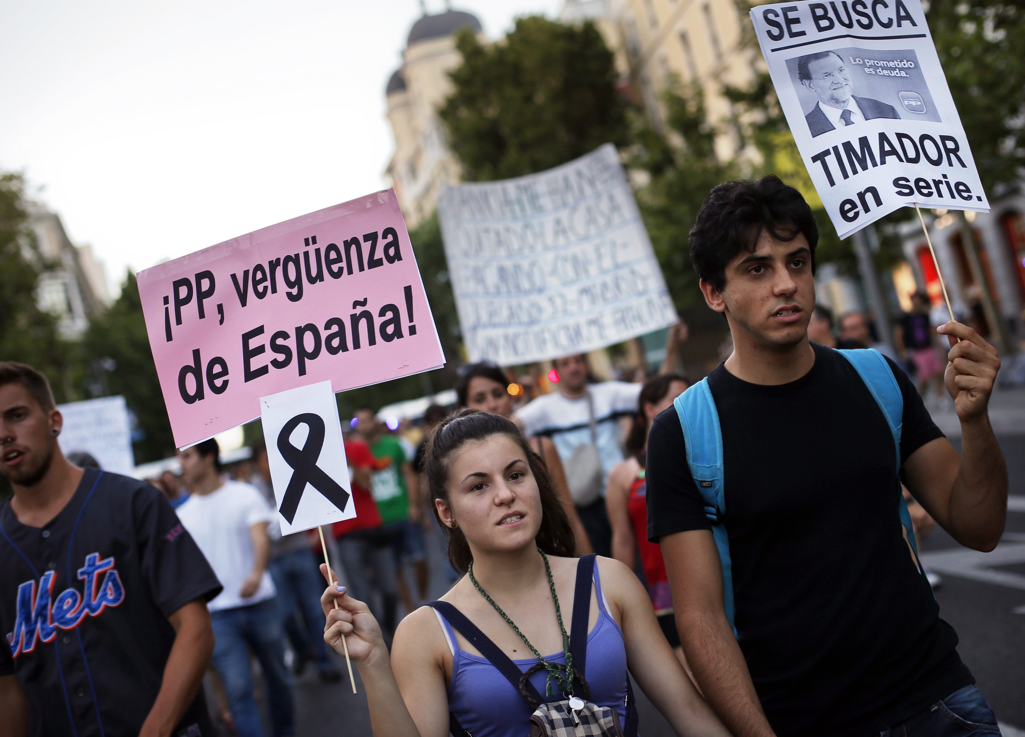 A demonstrator holds a sign with a black ribbon hanging from it in memory of the victims of the train crash in Santiago de Compostela. Photo: Reuters