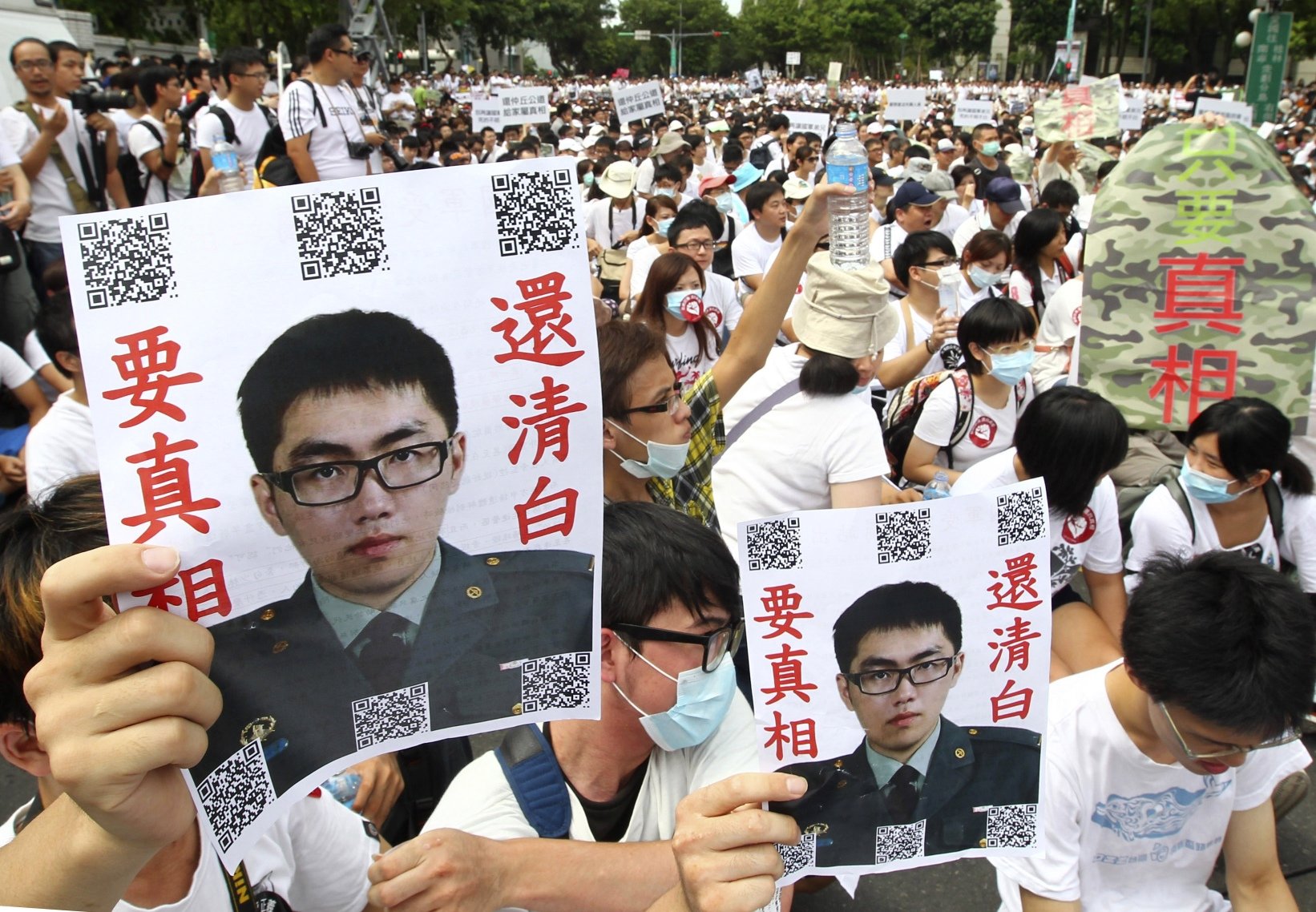 Taiwanese protesters hold posters that read "Give the truth" next to portraits of Taiwan soldier Hung Chung-chiu who died in early July after being forced to perform a vigorous regime of calisthenics in sweltering heat on a base in suburban Taipei. Photo: AP