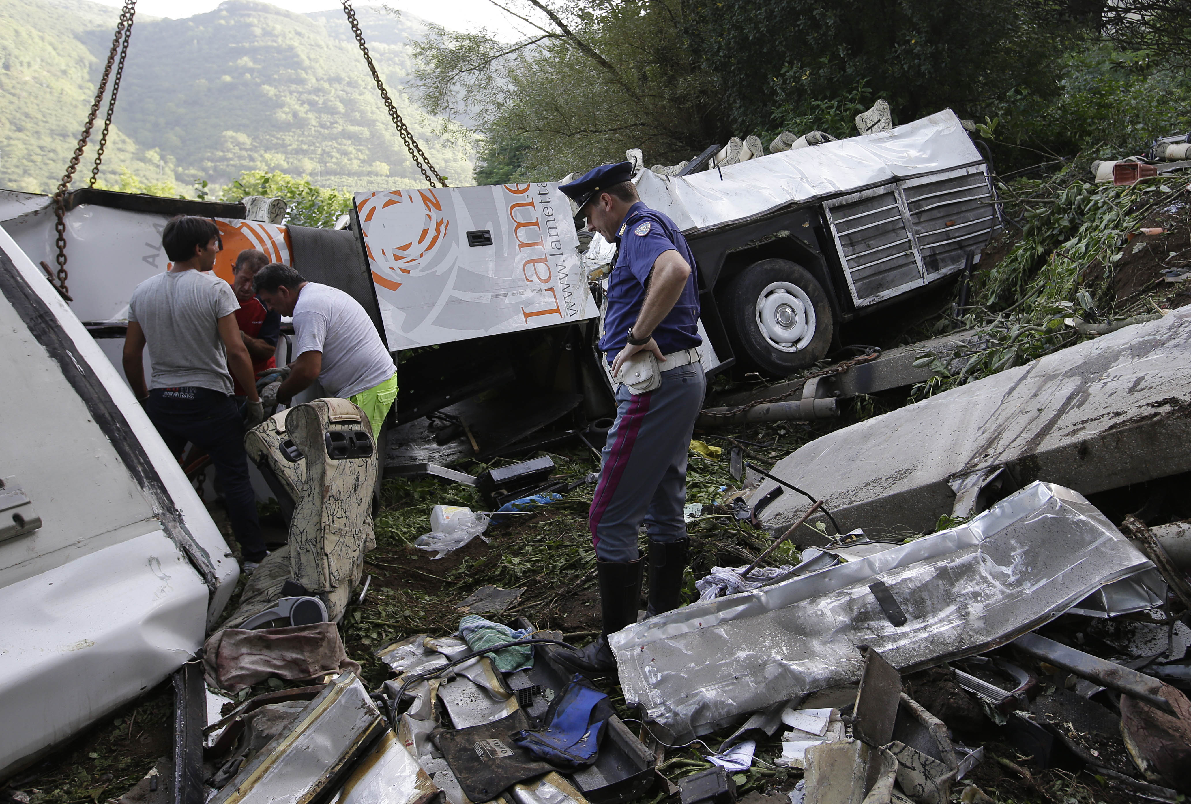 A Carabiniere police officer looks at the wreckage of a bus which crashed near Avellino. Photo: AP