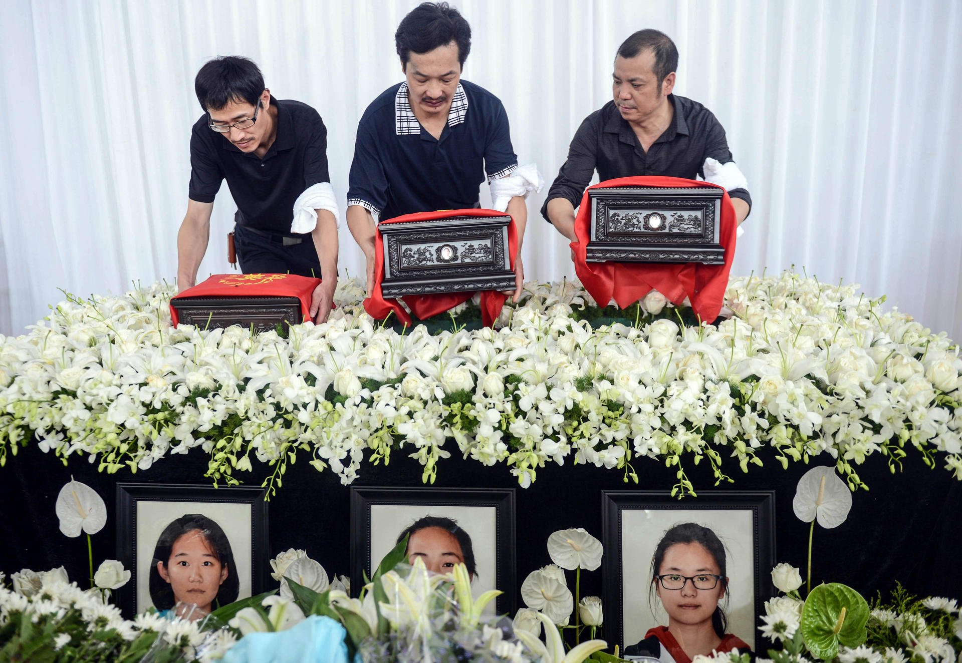 The fathers of pupils (from left) Liu Yipeng, Wang Linjia and Ye Mengyuan - victims of the Asiana plane crash in San Francisco - carry their daughters' urns at a service in Jiangshan yesterday. Photo: Xinhua