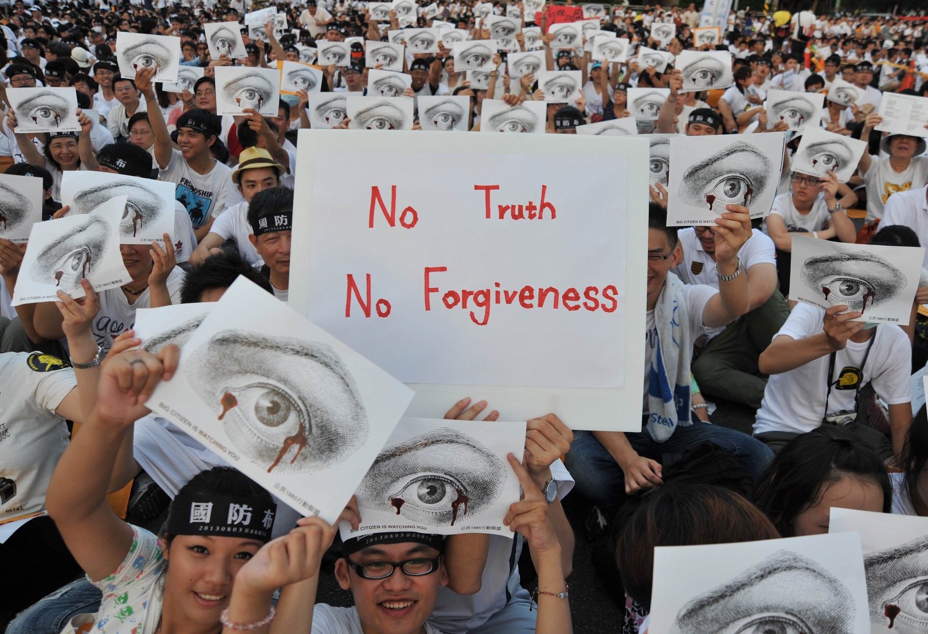 Protesters hold placards as they sit during an anti-military rally in front of Taiwan's presidential office in Taipei on Saturday. Photo: AFP