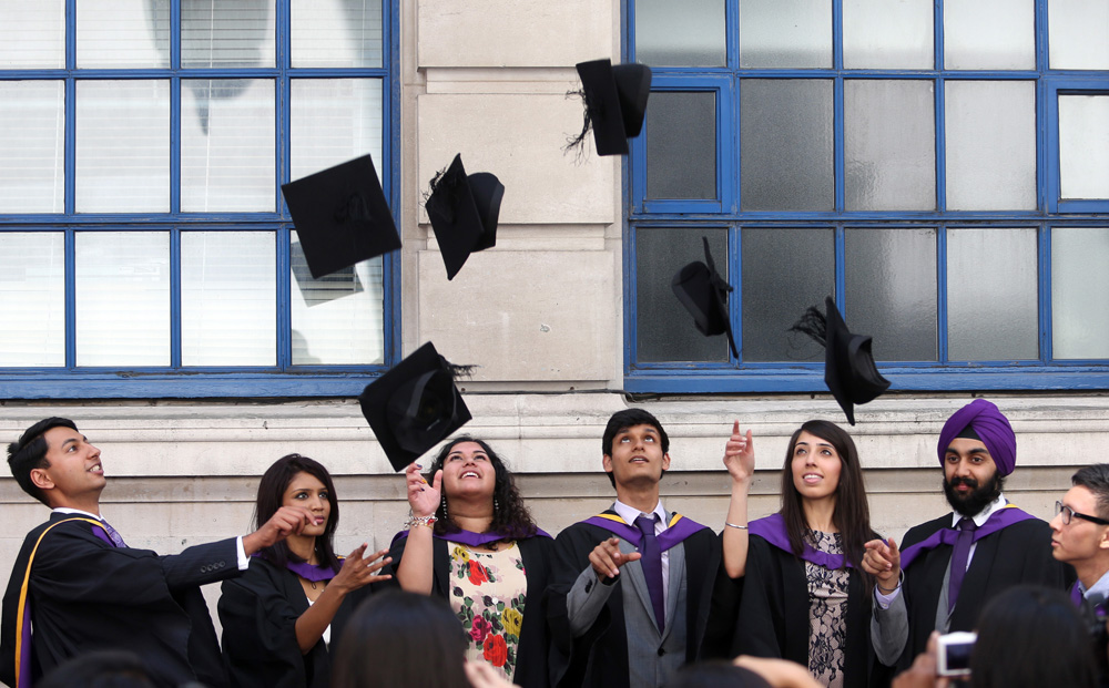 Students from the London School of Economics & Political Science (LSE) throw their mortar boards into the air in celebration during a ceremony for university graduates. Photo: Bloomberg