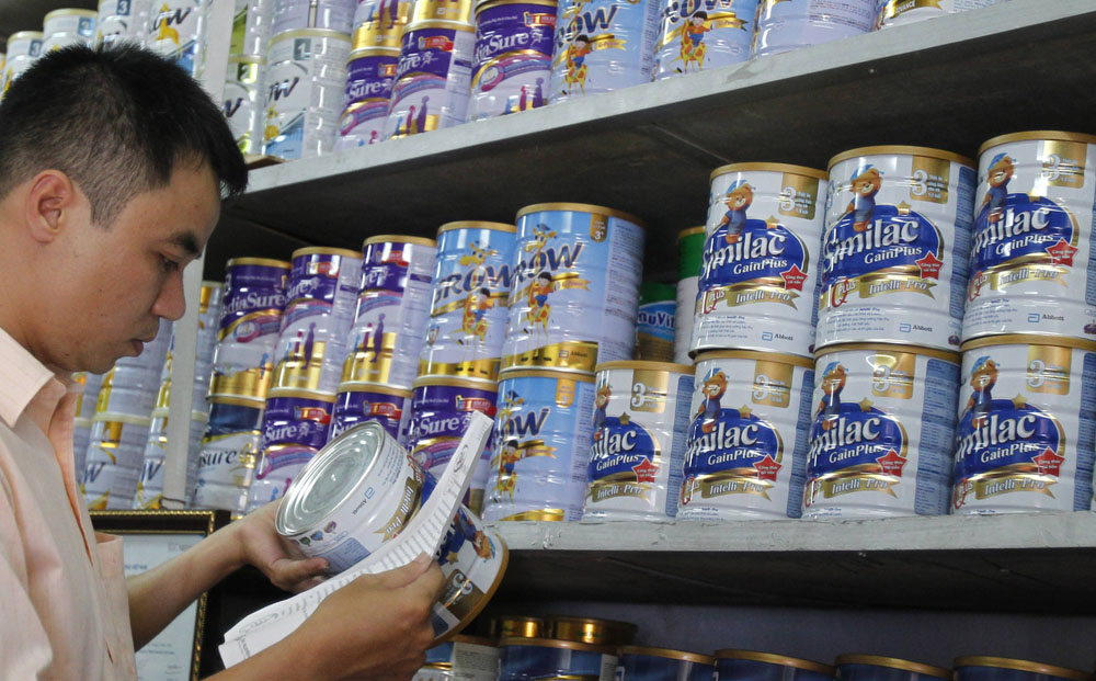 An Abbott Laboratories sales staff checks the serial number of a powder milk tin during a production recall at a milk shop outside Hanoi. Photo: Reuters
