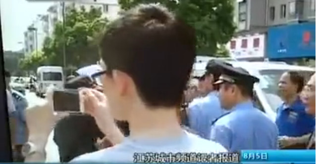 A man films local urban management officers. Photo: Screenshot from Sina