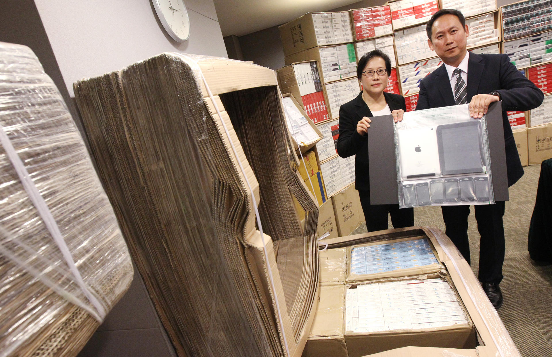 Customs' Lai Sau-ieng (left) and Wan Hing-chuen show seized cigarettes, tablet computers and mobile phones. Photo: David Wong