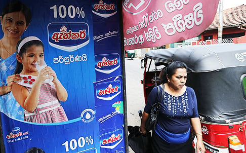 A Sri Lankan woman walks past an advertisement of a Fonterra product in Colombo, Sri Lanka. Photo: AP