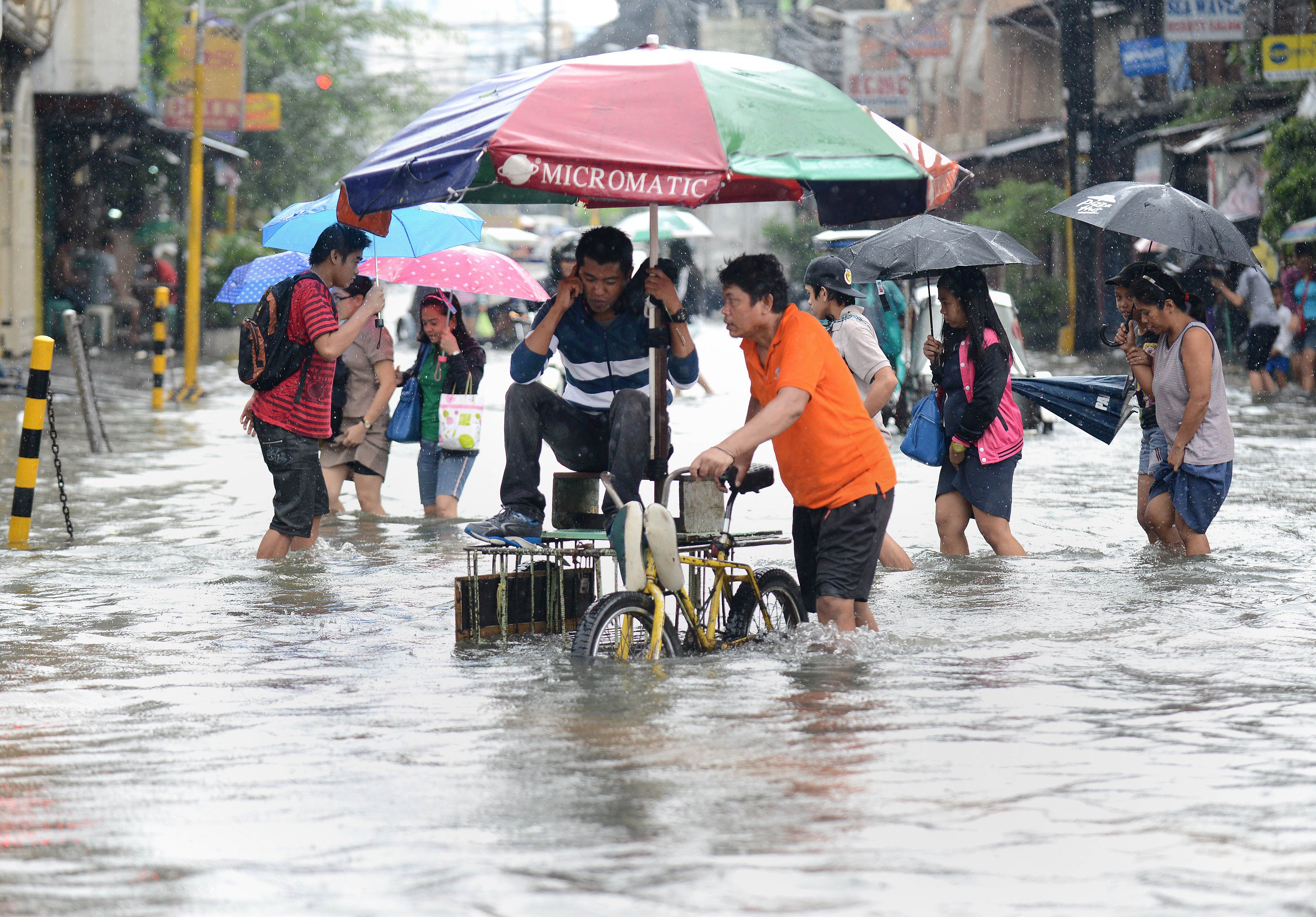 Residents wade through a flooded street in Manila. Photo: AFP