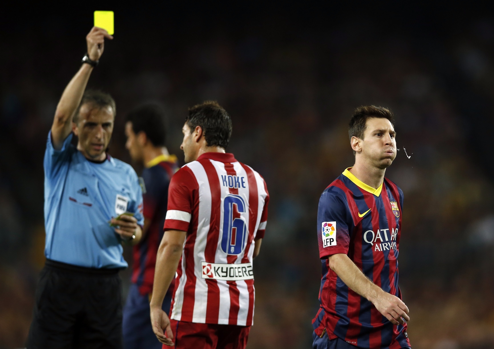 Referee Fernandez Borbalan gives a yellow card to Atletico Madrid's Koke (C) as Barcelona's Lionel Messi (R) walks away during their Spanish Super Cup second leg soccer match at Camp Nou stadium in Barcelona. Photo: Reuters