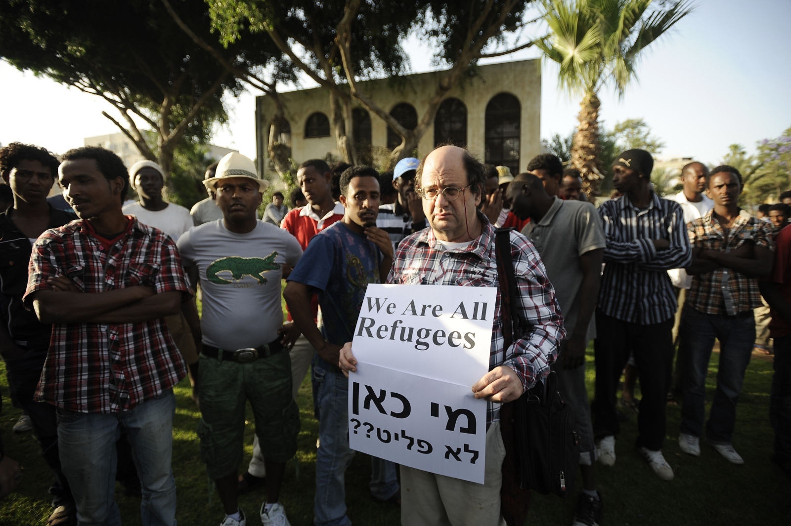 An protester in Tel Aviv stands next to African migrants holding a slogan condemning Israel's policy towards African migrants. Israel plans to deport migrants from Eritrea and Sudan. Photo: AFP 