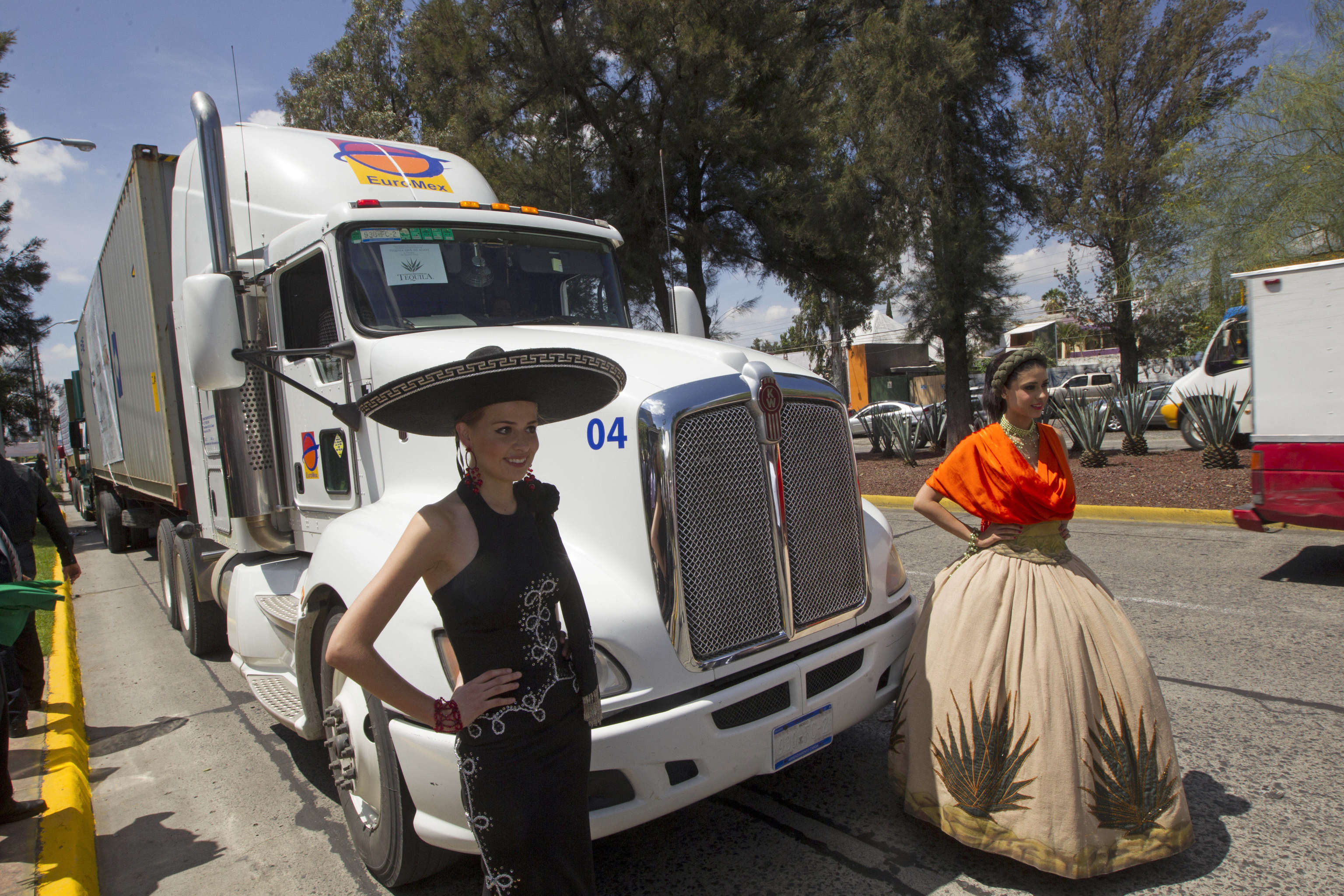Women dressed in costumes stand in front of a line of cargo trucks during a ceremony marking the departure of the first load of blue agave tequila to China in Zapopan, Mexico. Photo: AP