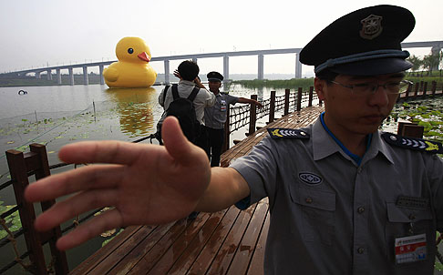 Security guards try to prevent photographers taking pictures of the inflated rubber duck created by Dutch artist Florentijn Hofman in Beijing on Sunday. Photo: Reuters