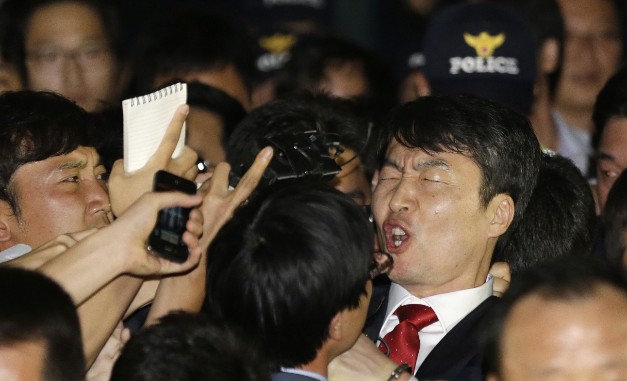 South Korean lawmaker Lee Seok-ki of the leftist Unified Progressive Party, right, shouts as he is surrounded by police officers and reporters after being arrested at the Suwon police station in Suwon, south of Seoul. Photo: AP