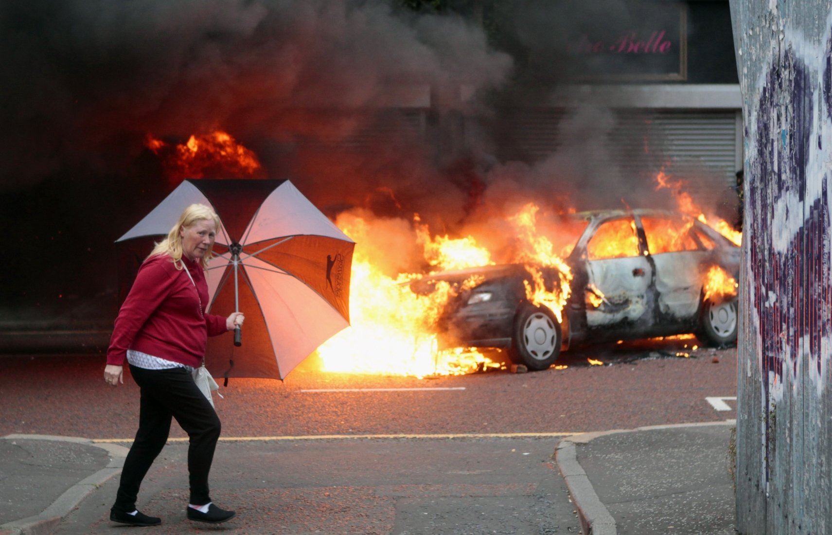 A woman walks past a burning car in the centre of Belfast. Amnesty said many abuses in Northern Ireland still remain hidden. Photo: AP