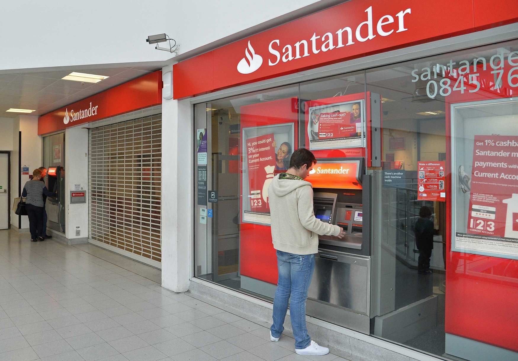 Customers use ATM machines at the Surrey Quays branch of Santander Bank, in south London. Four men have been charged over the Santander cyber plot. Photo: Reuters