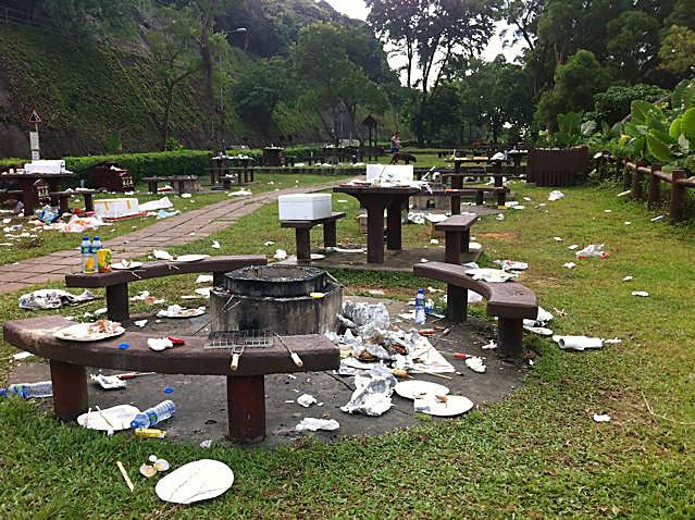 Litter is strewn across a picnic site while bins lie empty.