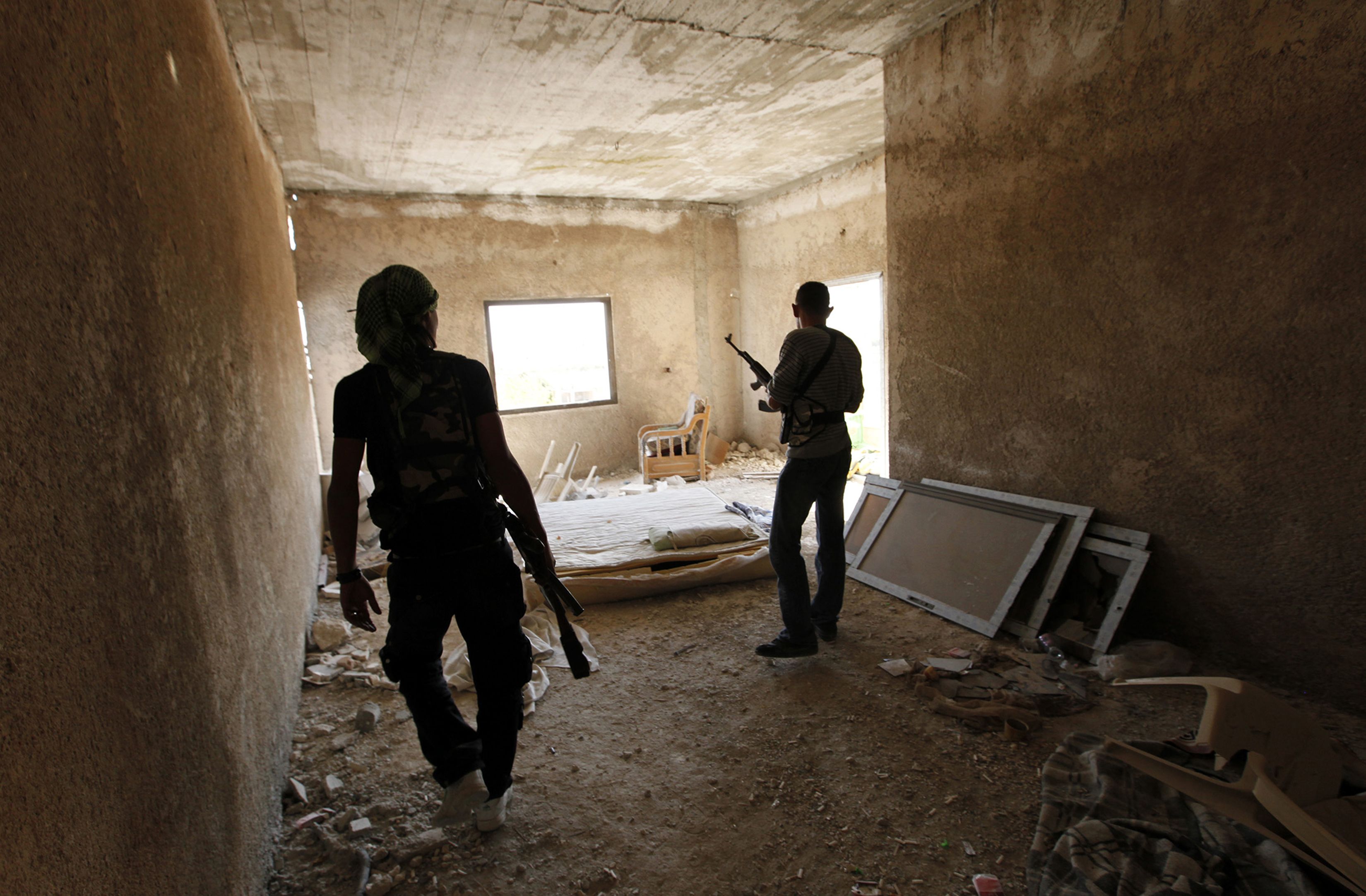 Free Syrian Army fighters walk with their weapons inside a damaged building beside the Syrian Regime Air Intelligence centre in Aleppo. The Syrian Observatory for Human Rights says that an air strike on a high school in Raqa killed 12 people. Photo: Reuters