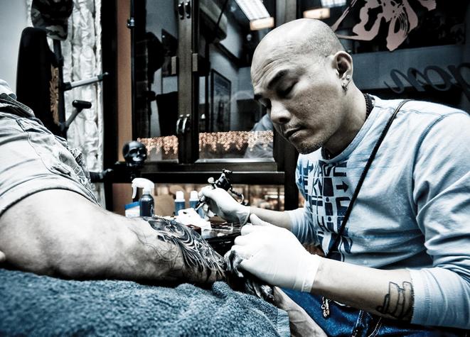 Gabe Shum applies some ink to his tattoo convention partner, Jay FC. Photo: Red Dog Studio