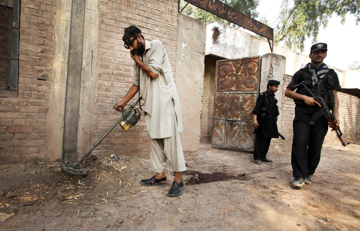 A security official uses a metal detector to survey the site of a bomb blast in the outskirts of Peshawar. Photo: Reuters