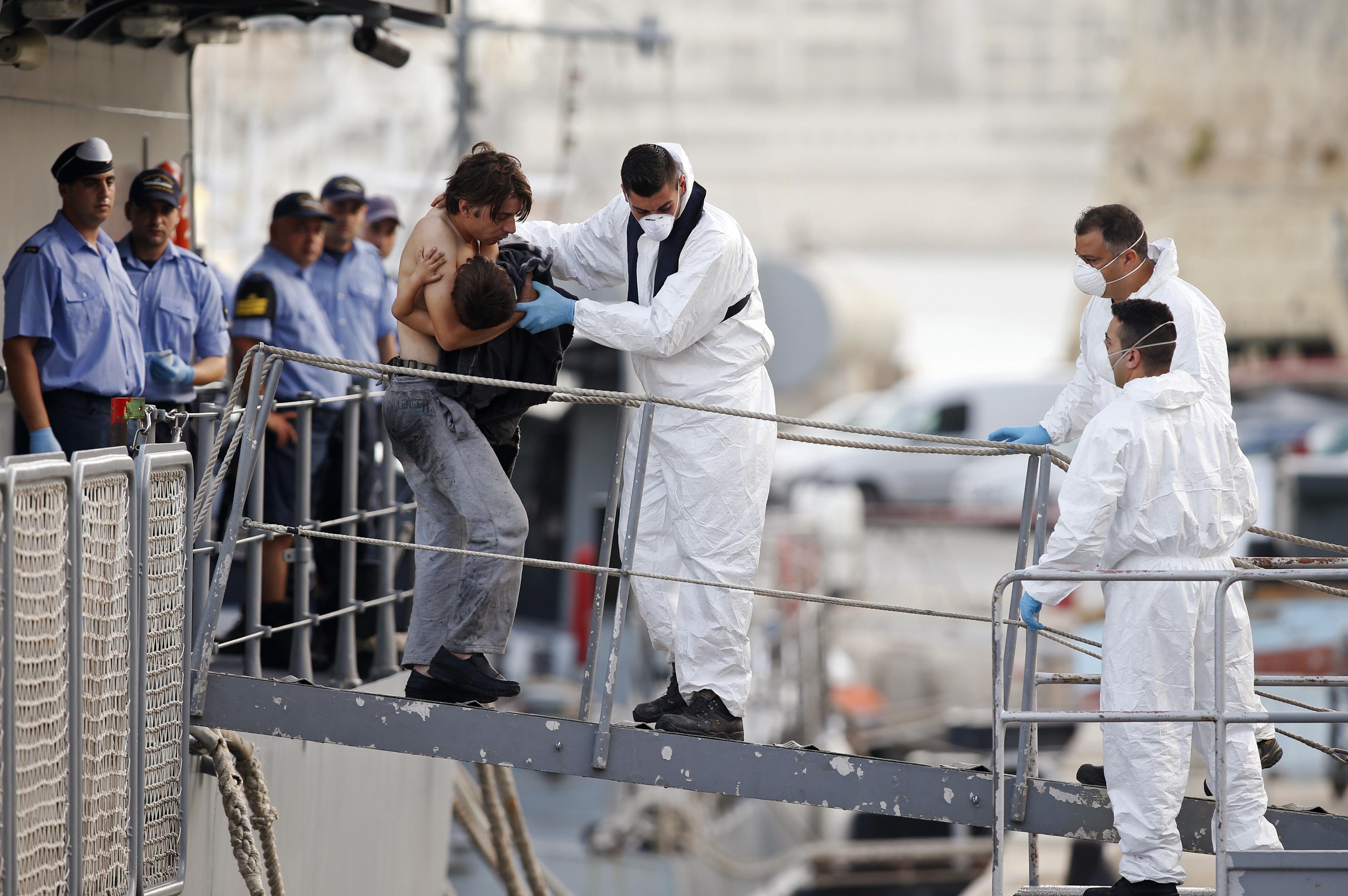 A rescued migrant carries his child as he disembarks from an Armed Forces of Malta ship. Photo: Reuters