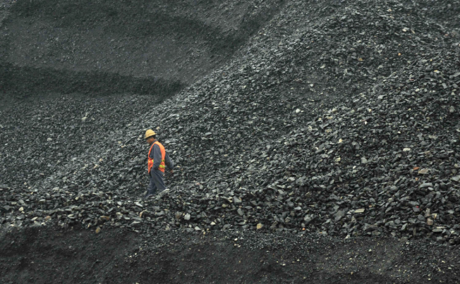 A labourer walks amid piles of coal at an opencast coal mine in Fuxin, Liaoning province. Photo: Reuters