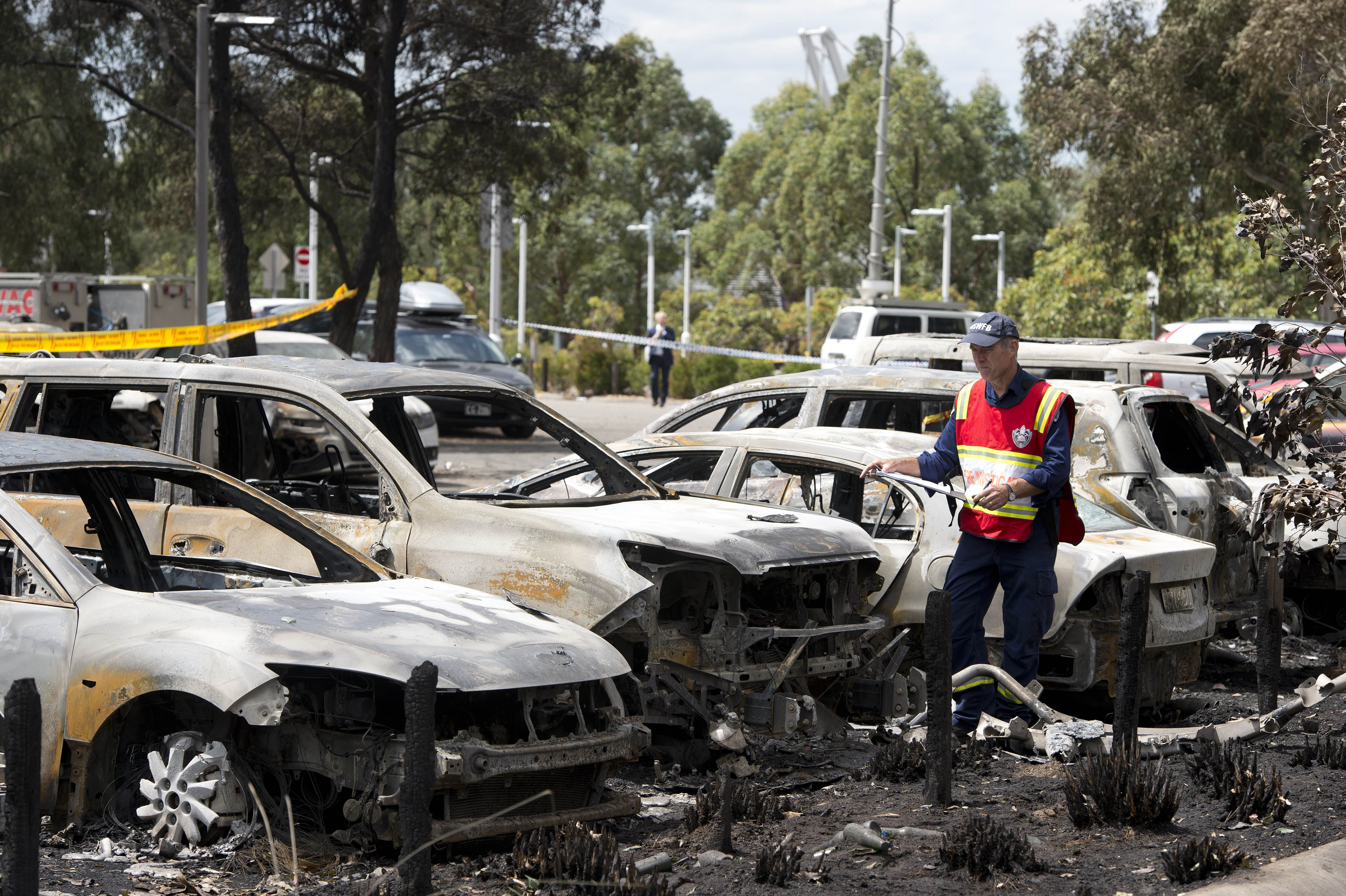 A fire investigator examines burnt vehicles following a fire at Sydney's Olympic Park. Photo: AFP