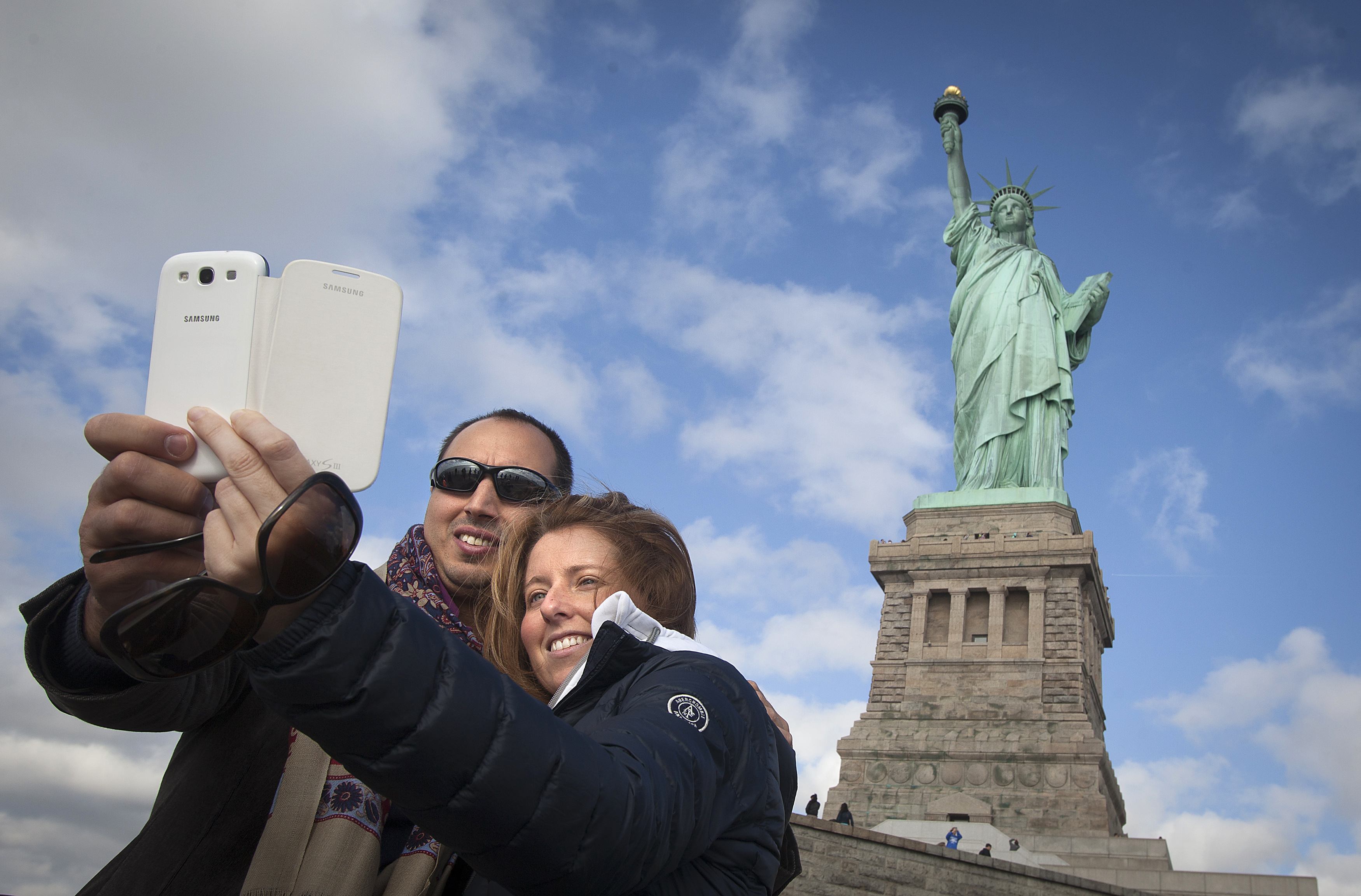 Tourists pose for a photo in front of the Statue of Liberty on Liberty Island in New York. Photo: Reuters