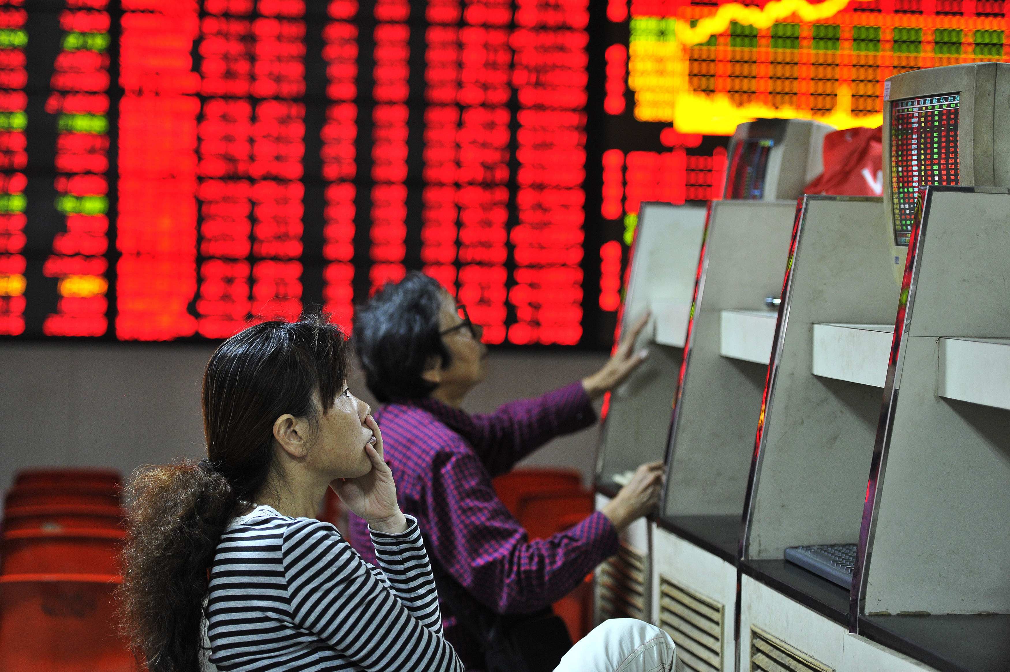 Investors look at computer screens in front of an electronic board showing stock information at a brokerage house in Hefei. Photo: Reuters
