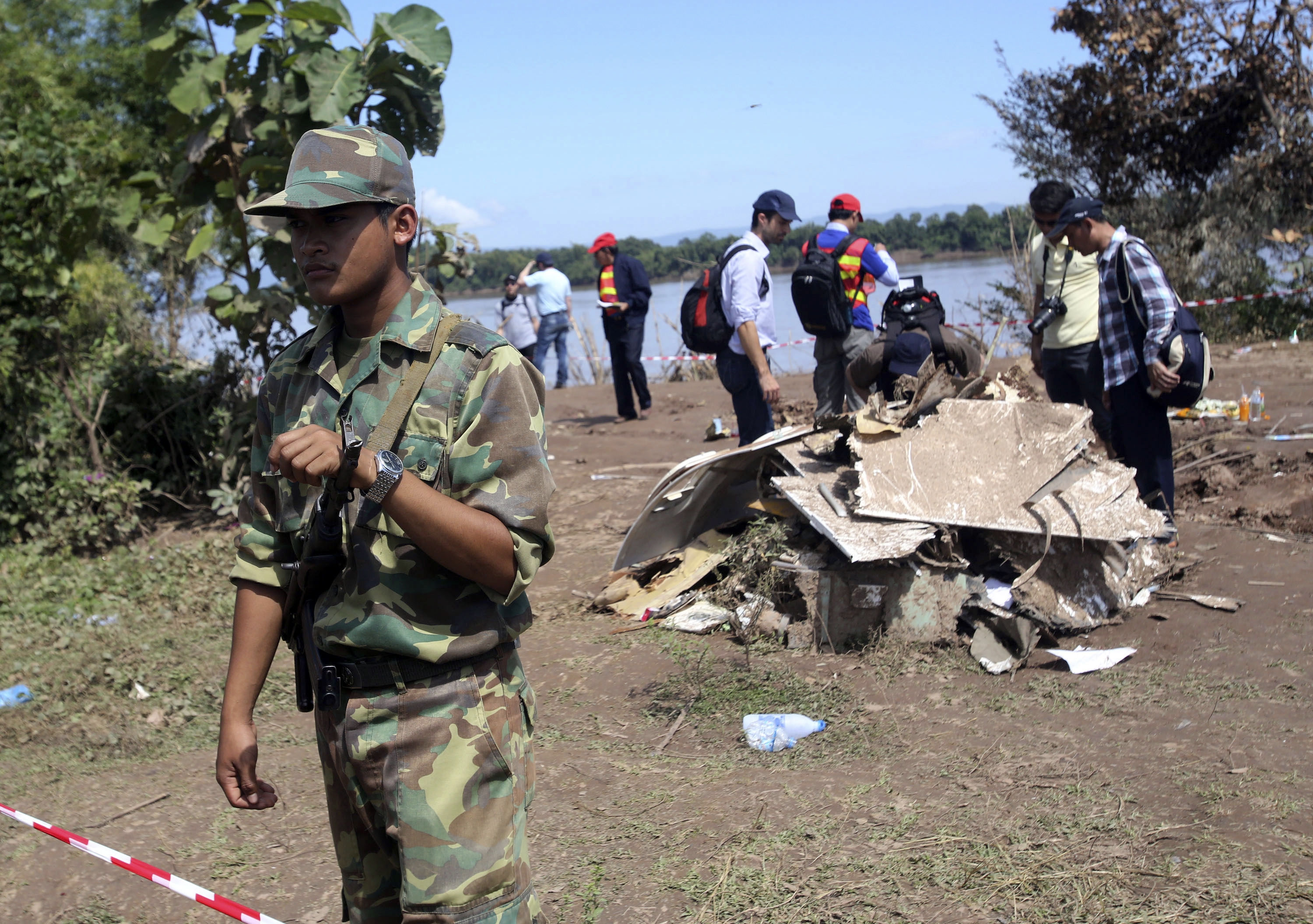 A Laotian soldier stands guard as French investigators gather around the wreckage of a Lao Airlines plane. Photo: AP
