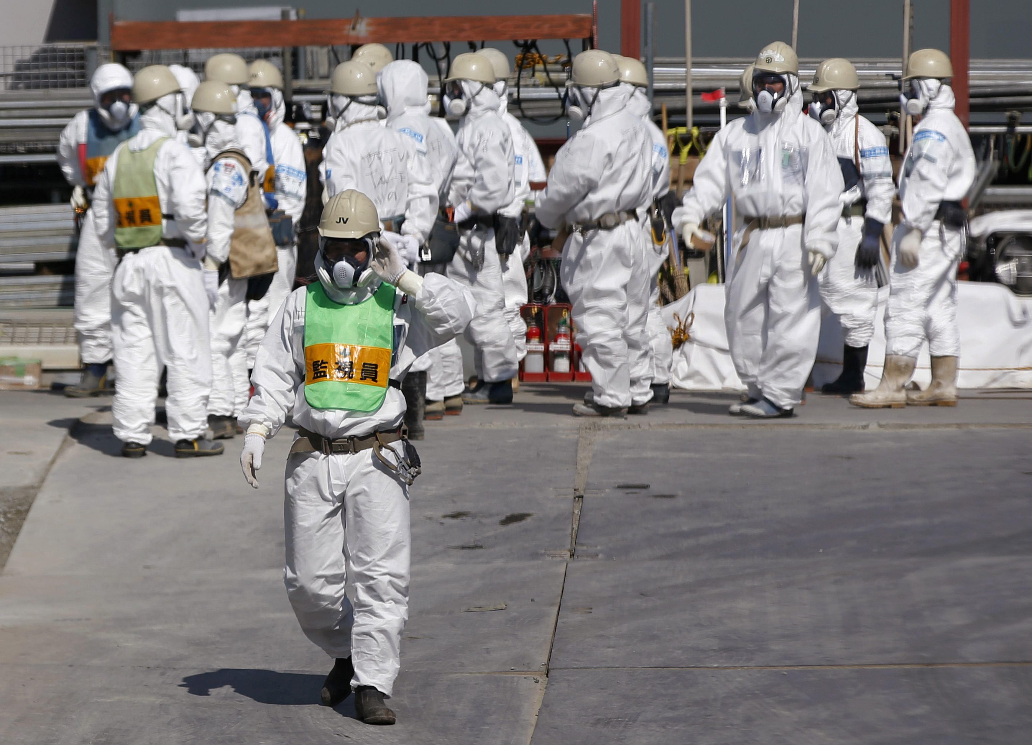 Workers wearing protective suits and masks at the Fukushima plant. A ruling party official has questioned a government plan to let evacuees return home. Photo: Reuters