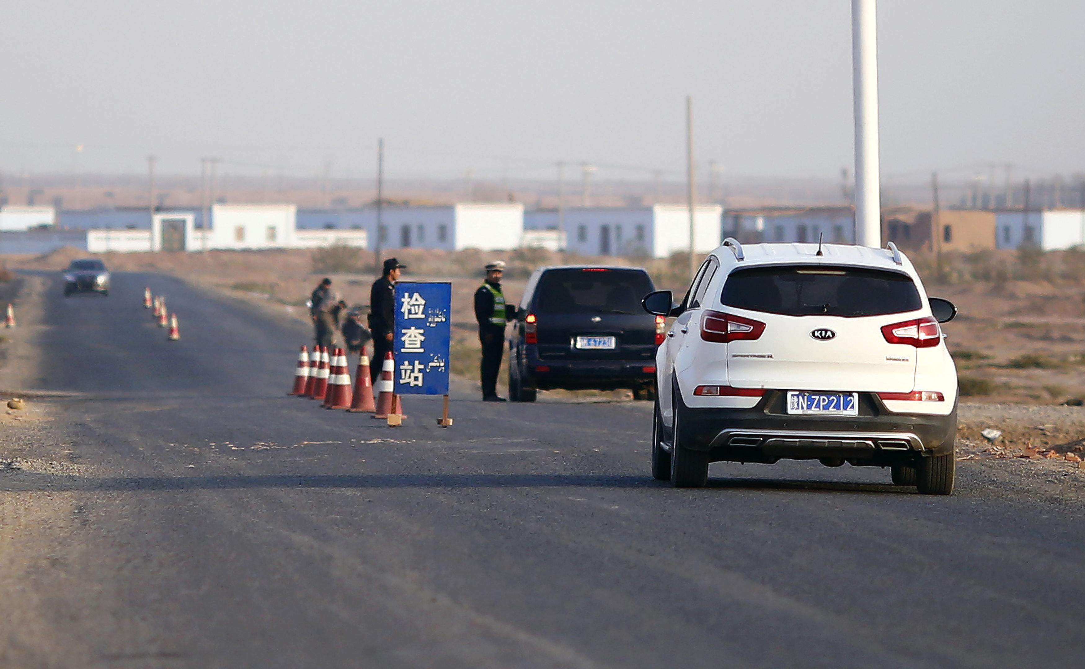 A police officer stops a car to check for identifications at a checkpoint near Lukqun, Xinjiang. Photo: Reuters