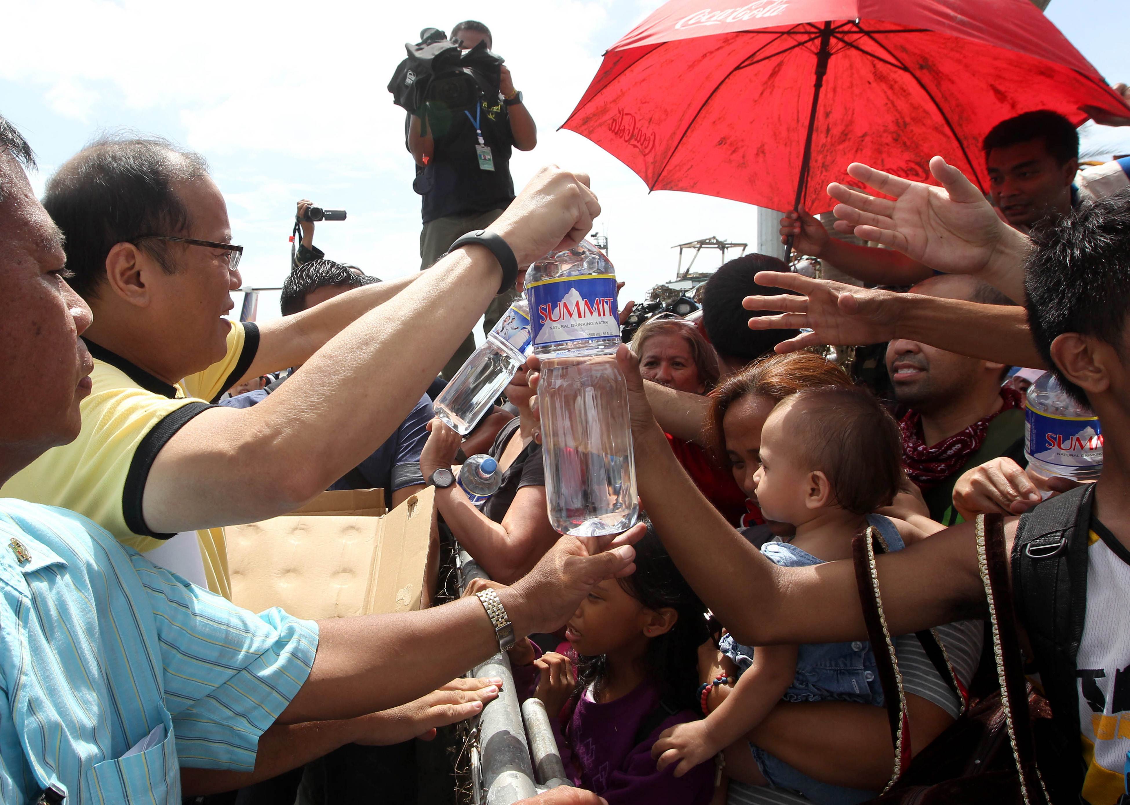 Philippines' President Benigno Aquino III distributes water to families displaced by Super Typhoon Haiyan. Photo: AFP