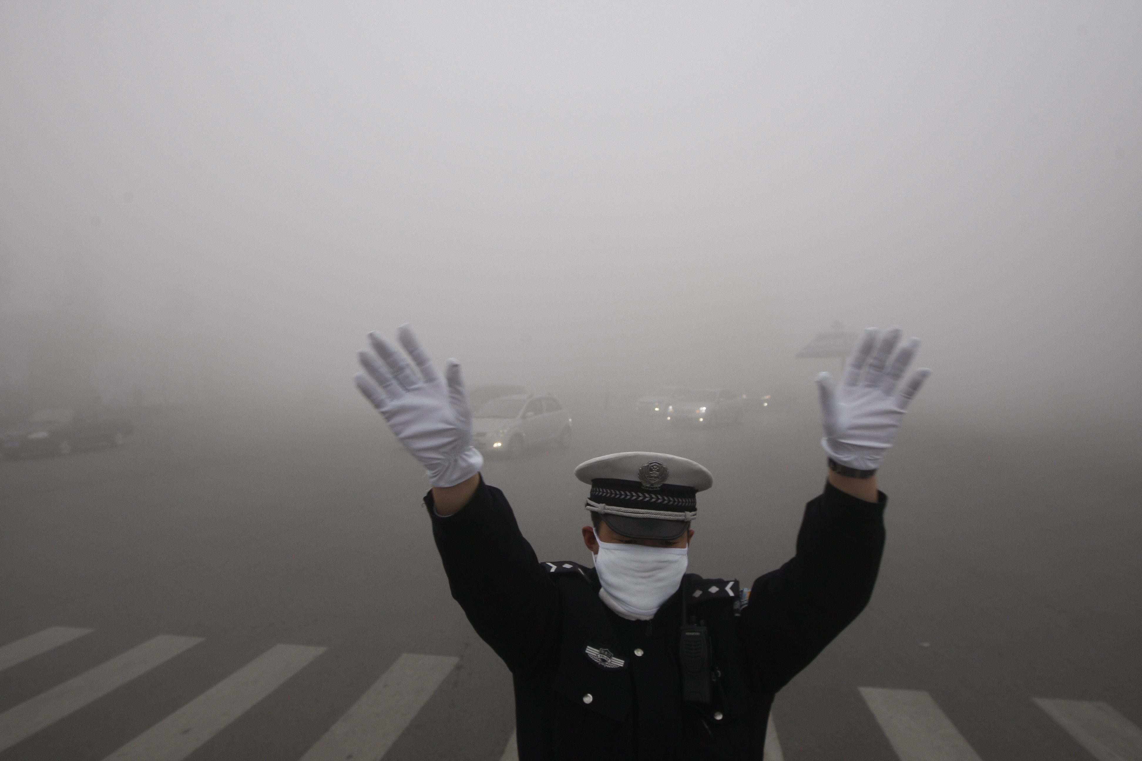 A policeman directs traffic during heavy smog in Harbin. Photo: EPA
