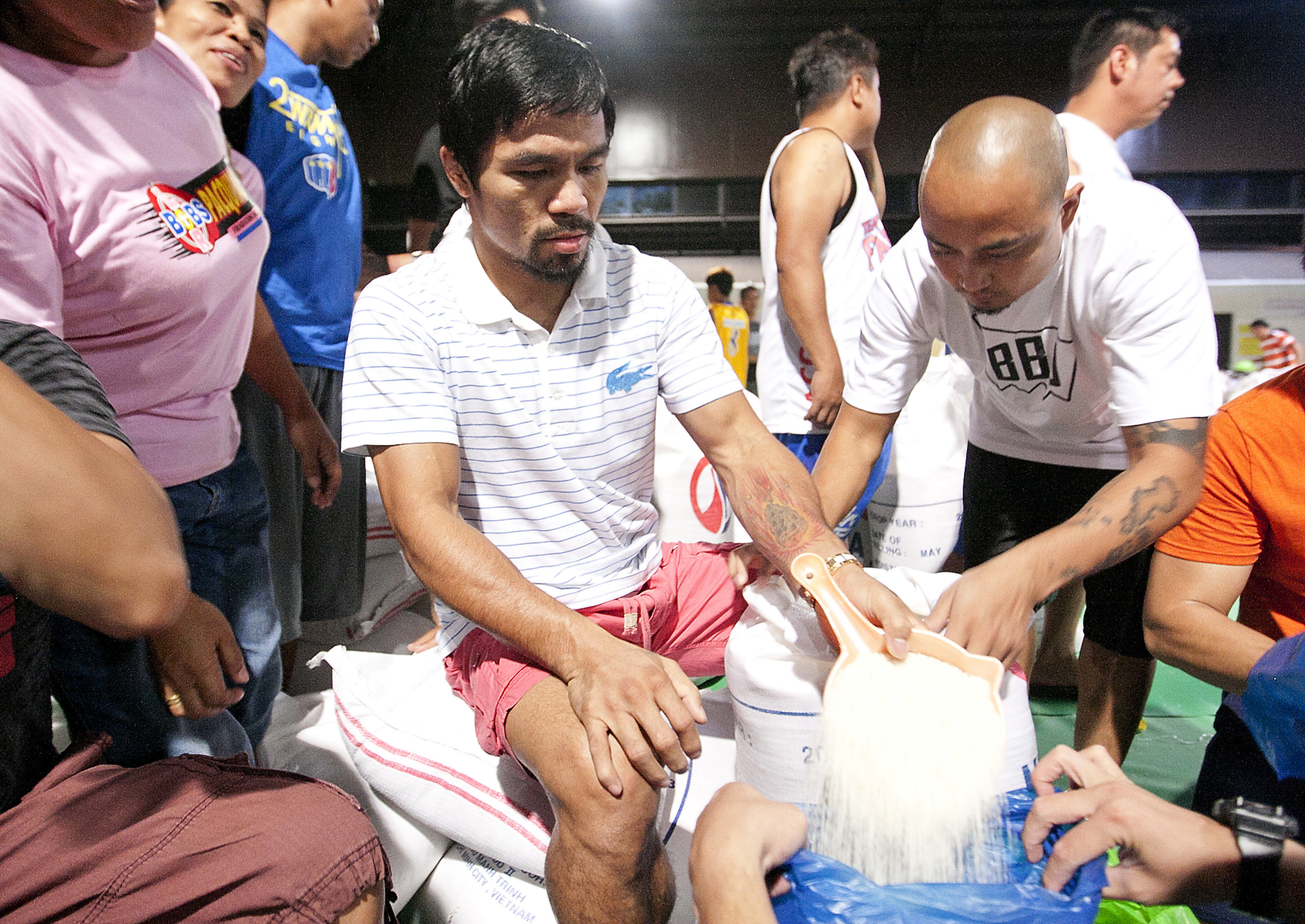 Filipino boxing icon Manny Pacquiao pours rice into a bag at a relief centre in General Santos, southern Philippines. Photo: AP