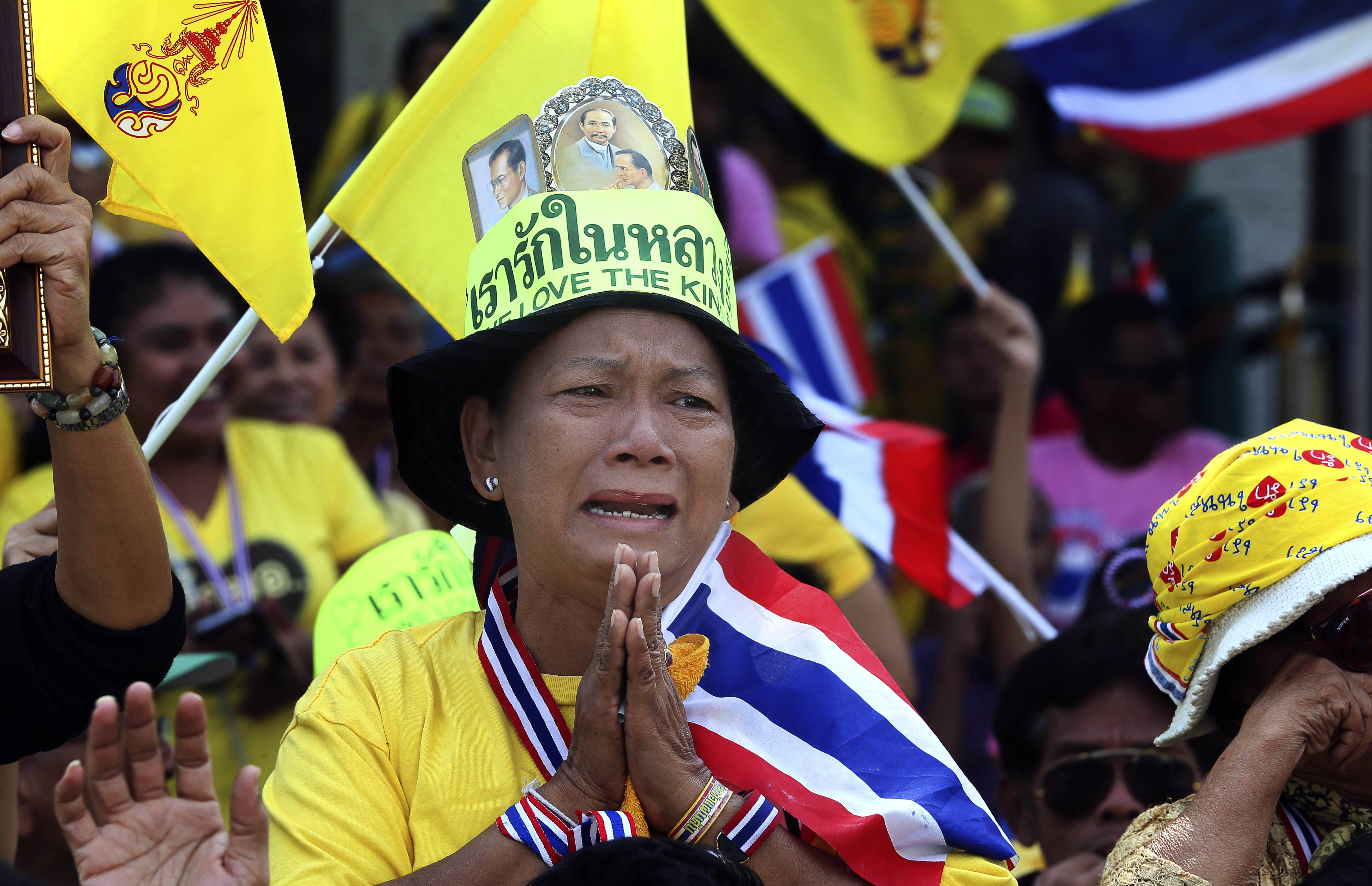 A Thai woman dressed in royal  yellow cries as she watches the king make a speech broadcast on a giant screen in Bangkok. Photo: AP