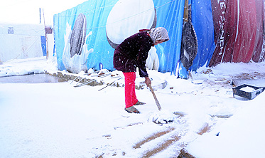 A Syrian refugee shovels snow outside her tent in the makeshift refugee camp of Terbol near the Bekaa Valley town of Zahleh in eastern Lebanon on Wednesday. Photo: AFP