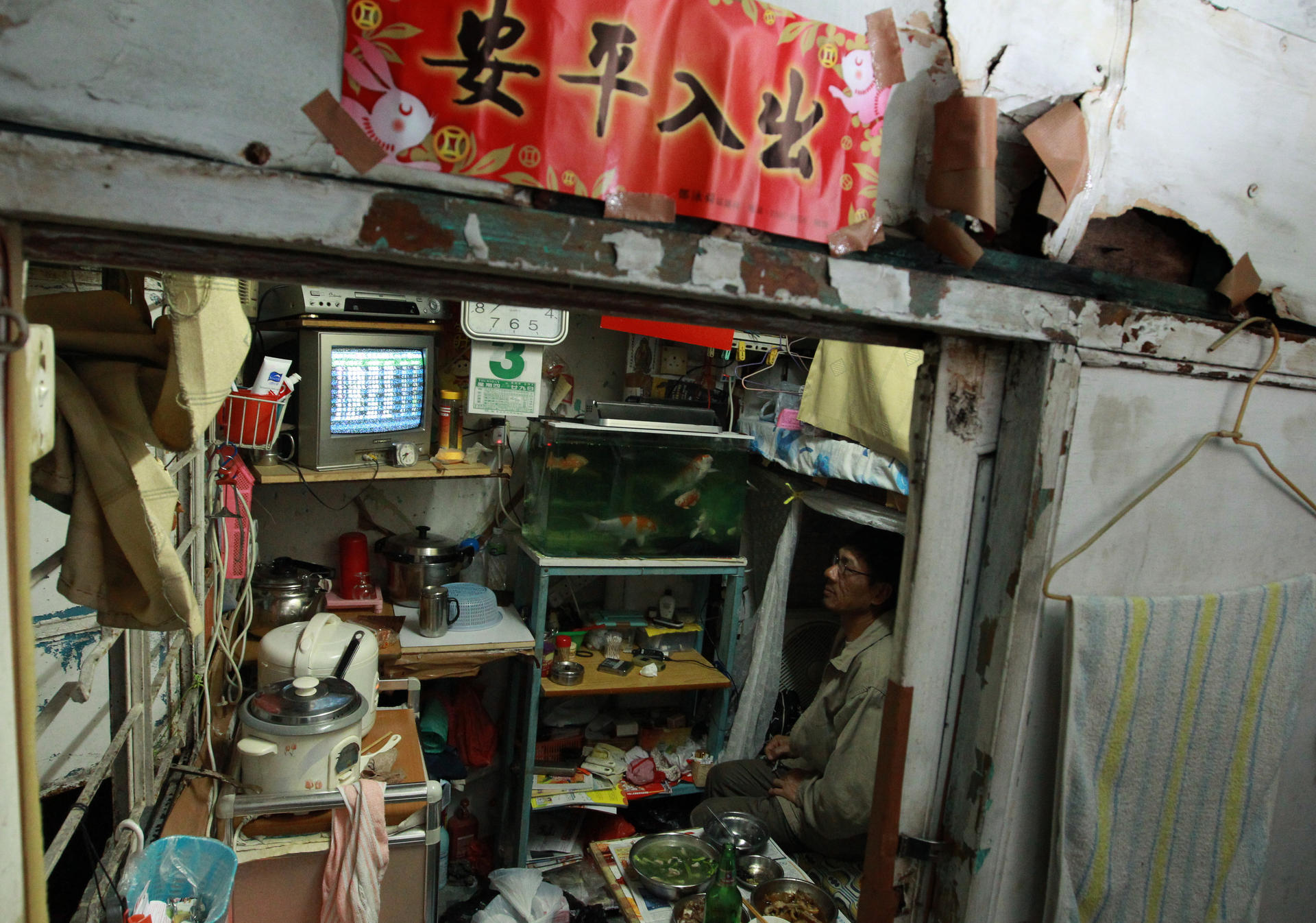 The modern face of poverty in Hong Kong. A man sits surrounded by his possessions in a cramped so-called cage home in Sham Shui Po. Photo: May Tse