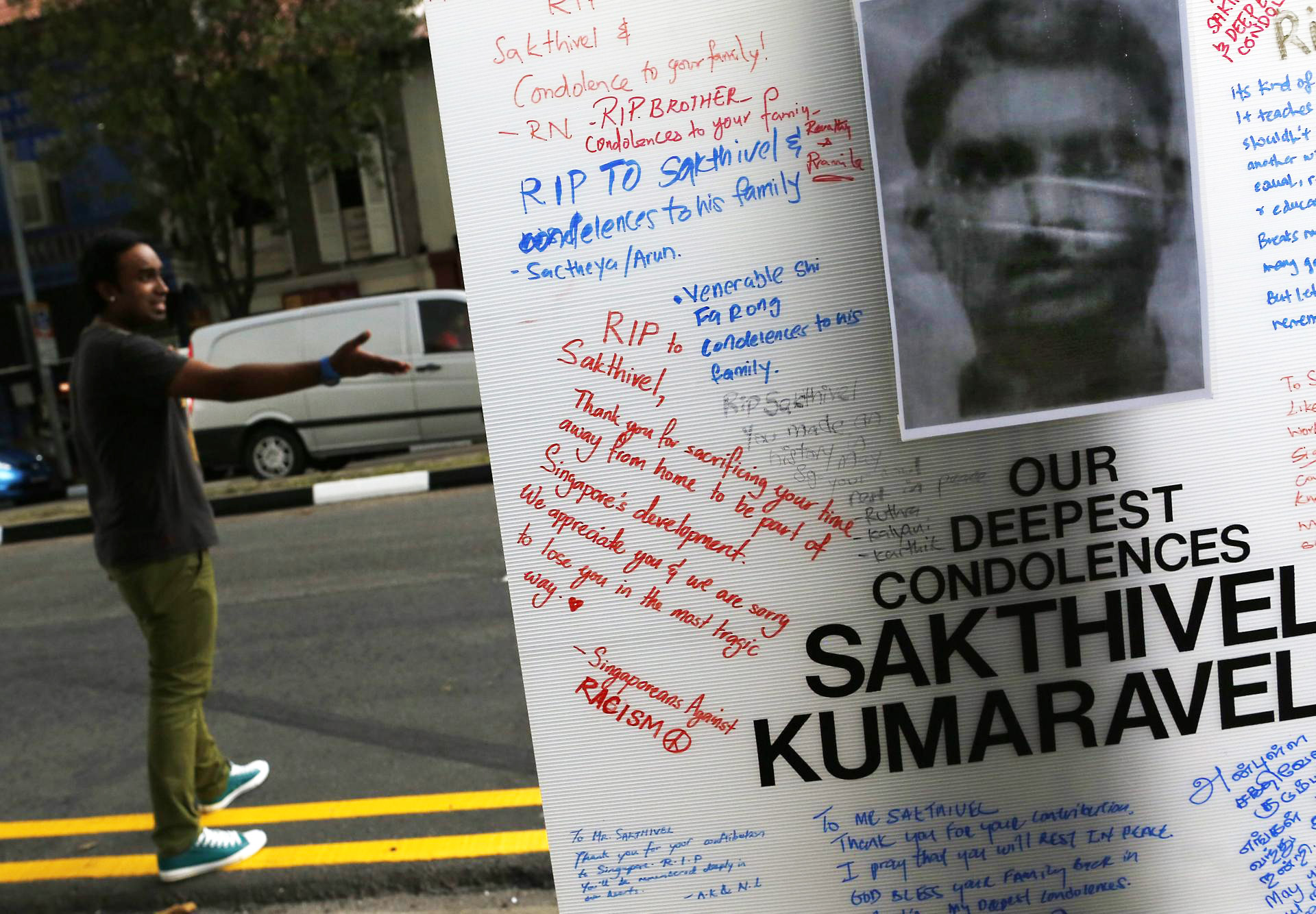A man gestures behind a tribute board for Sakthivel Kumaravelu, an Indian national who was killed when he was struck by a bus, sparking a riot in the Little India district of Singapore. Photo: EPA
