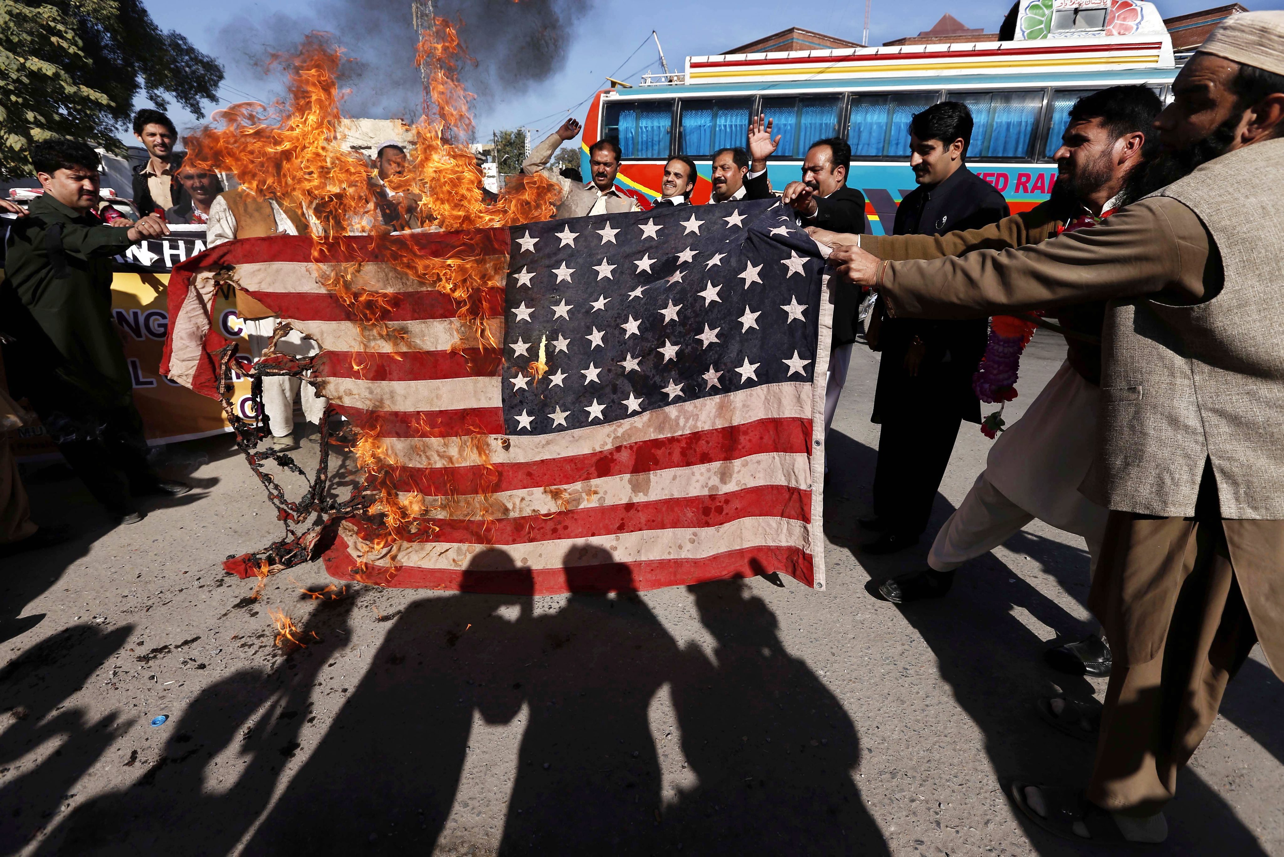 Pakistanis burn a US flag in Peshawar during a protest against US drone attacks. Photo: EPA