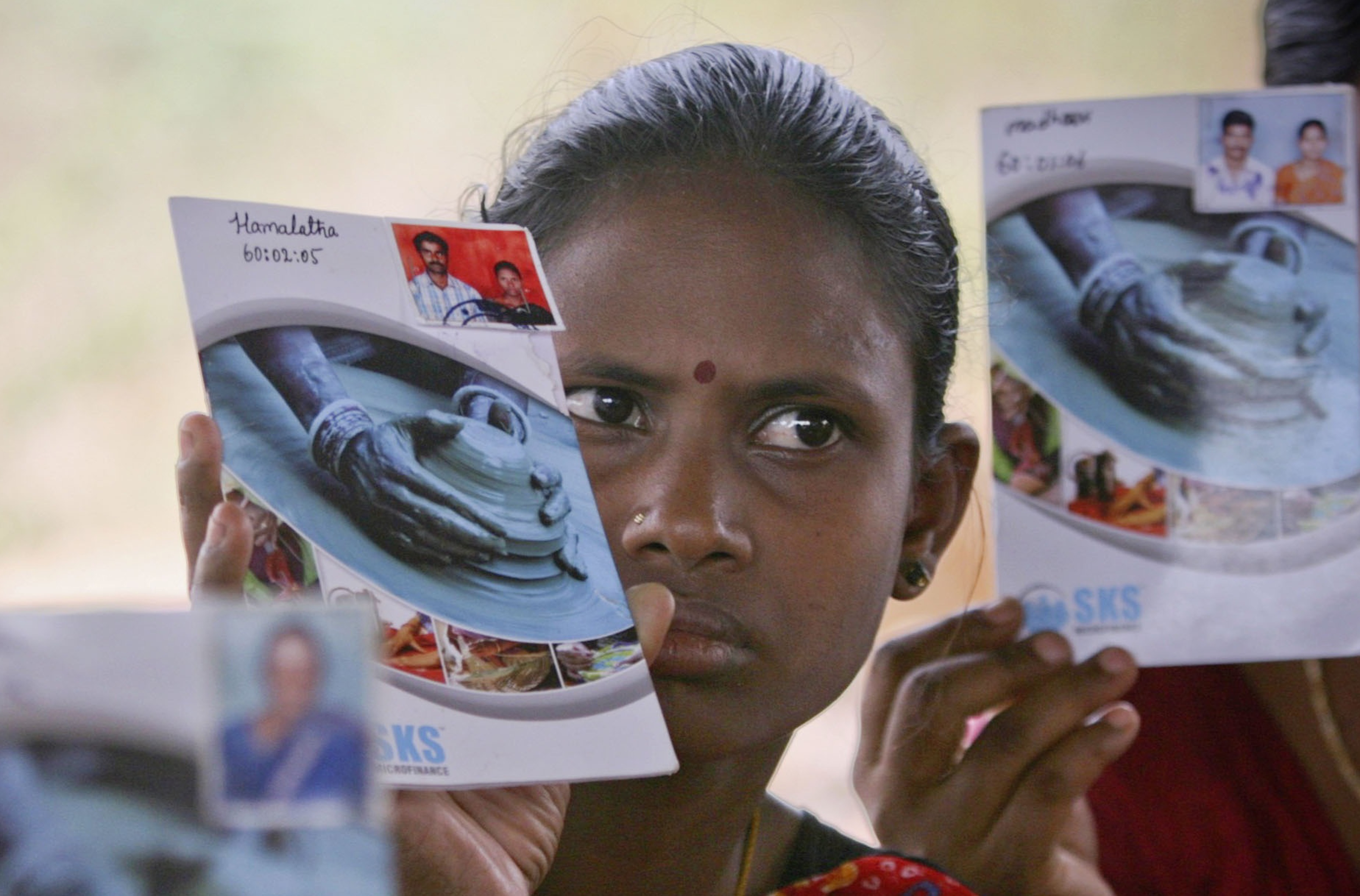 Hemalatha and other loan borrowers show pass books given to them by a micro finance company at Ibrahimpatnam, on outskirts of the southern Indian city of Hyderabad, May 19, 2011. Photo: Reuters