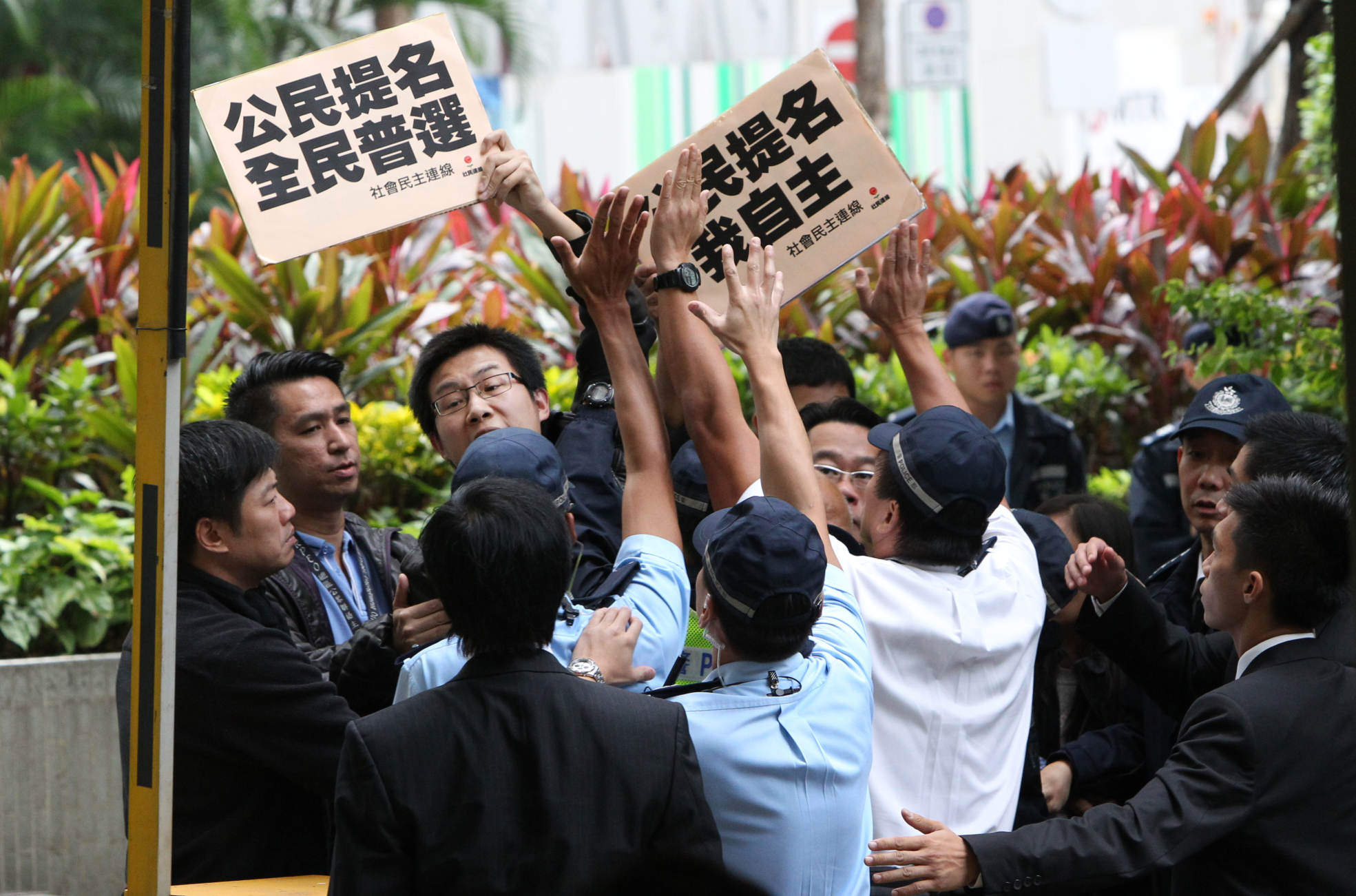 League of Social Democrats member Wong Ho-ming, left, protests as Basic Law Committee chairman Li Fei meets media in Hong Kong on November 21, 2013. Photo: SCMP/Felix Wong