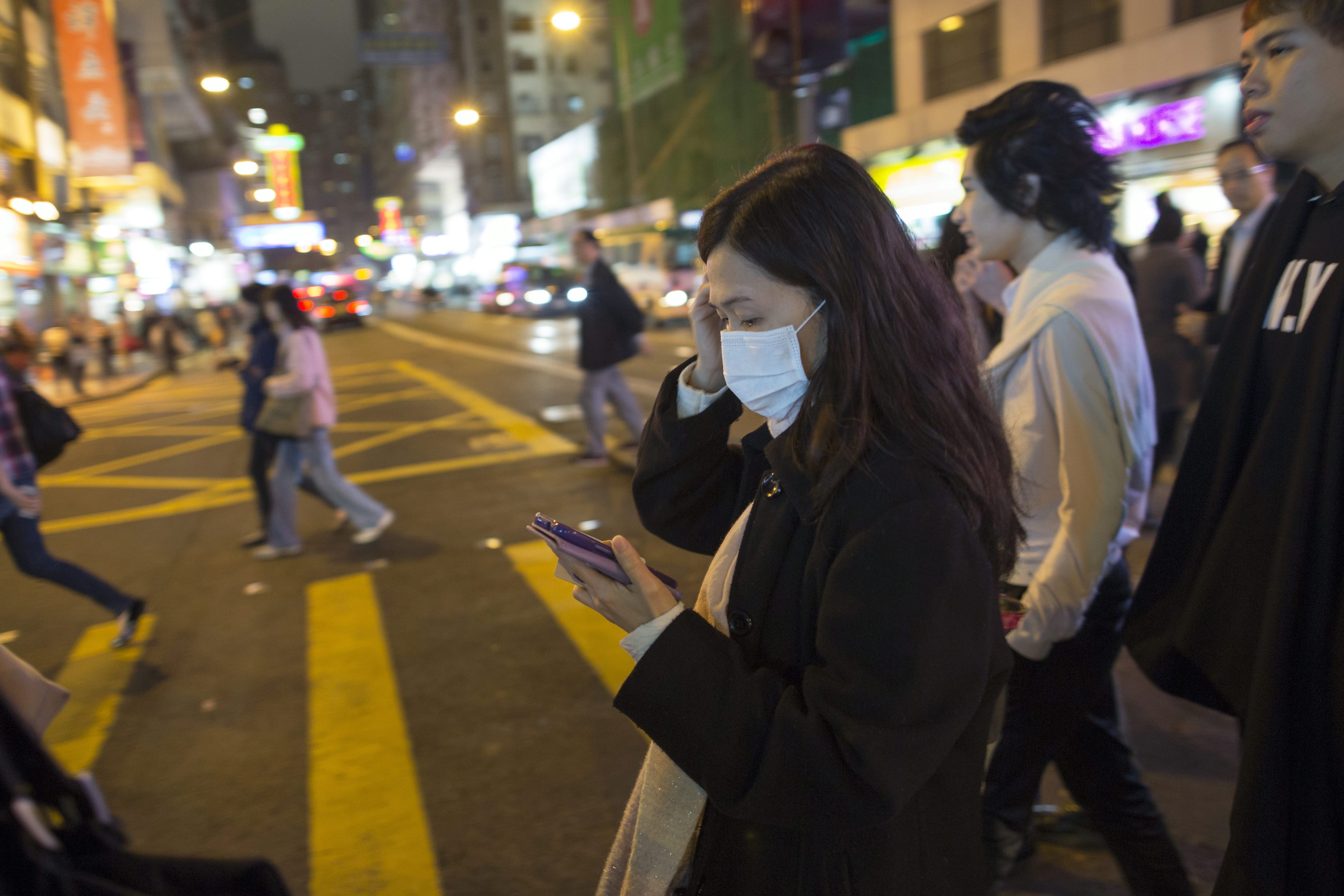 A woman uses smartphone while walking across the street. Photo: EPA