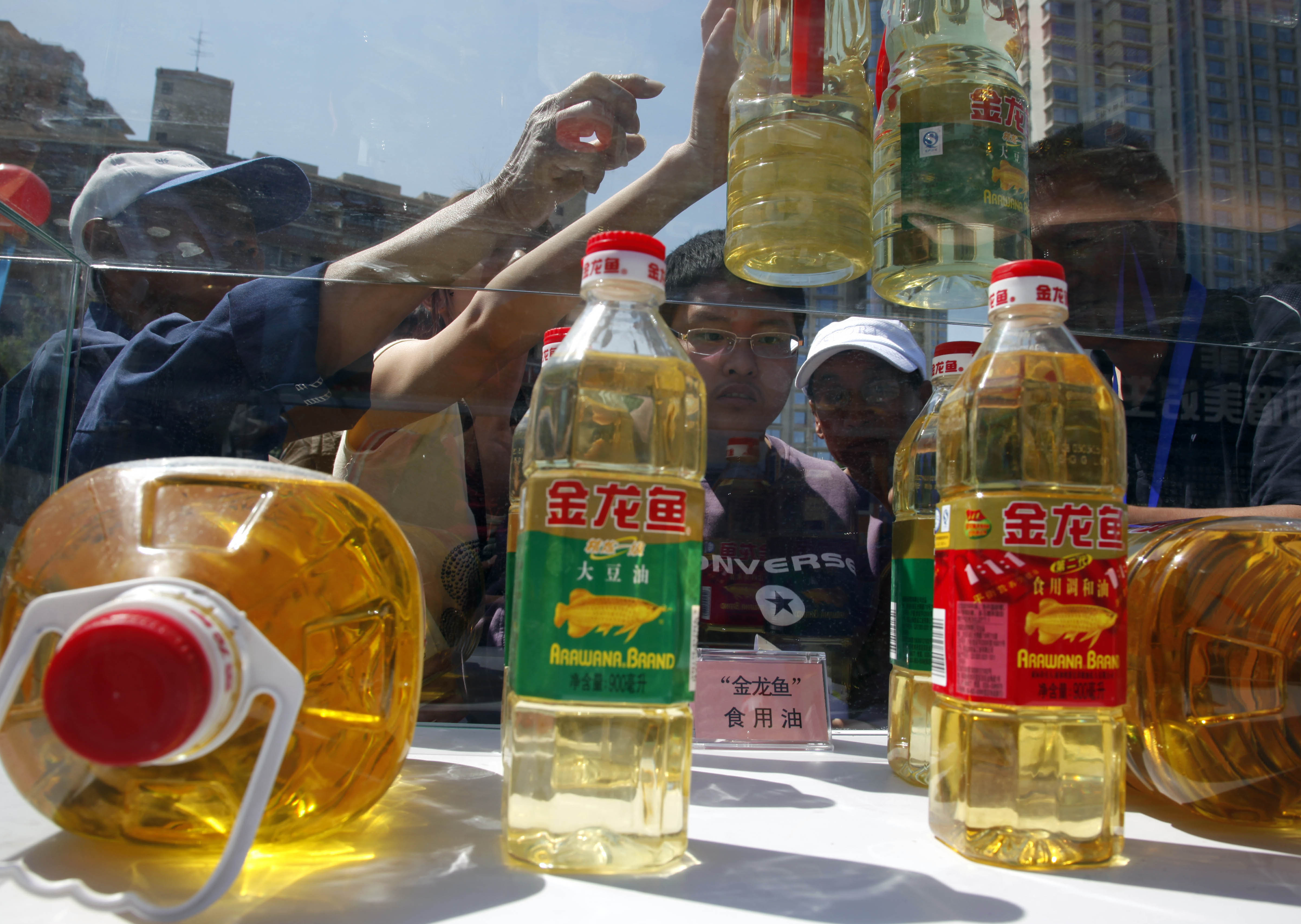 Beijing residents try to tell counterfeit cooking oil products from the real thing during an event to promote awareness of economic crimes. Photo: AP 