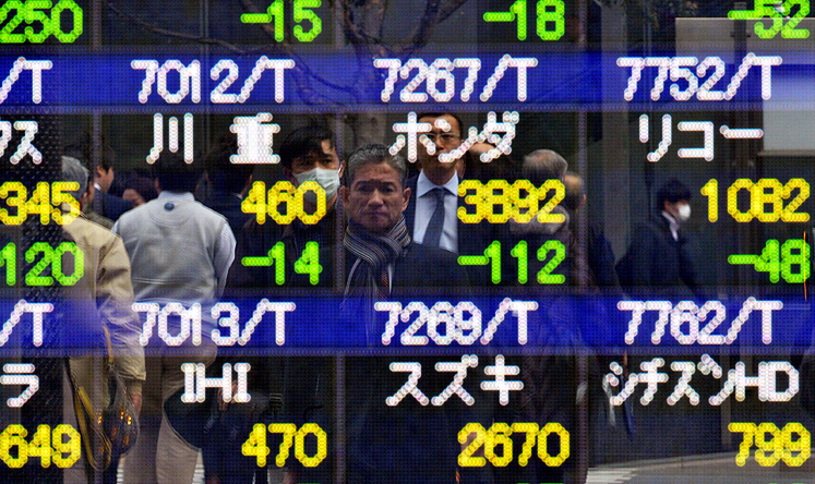 Pedestrians are reflected on a share prices board in Tokyo on Thursday. Photo: AP