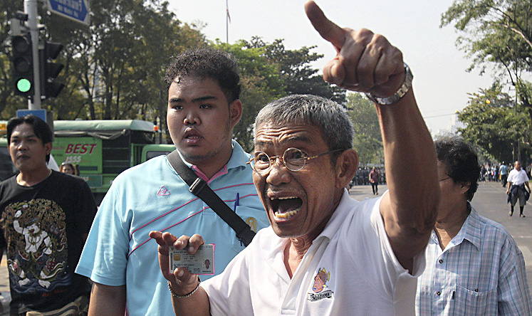 An angry Thai voter waves his ID card as he demands access to Din Daeng polling station in Bangkok on Sunday. Photo: AP