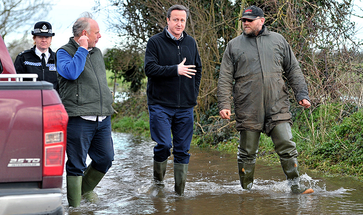 British Prime Minister David Cameron (centre) talks to Bridgwater and West Somerset MP Ian Liddell-Grainger (left) and farmer Tony Davy (right) during a visit to flooded areas. Photo: EPA